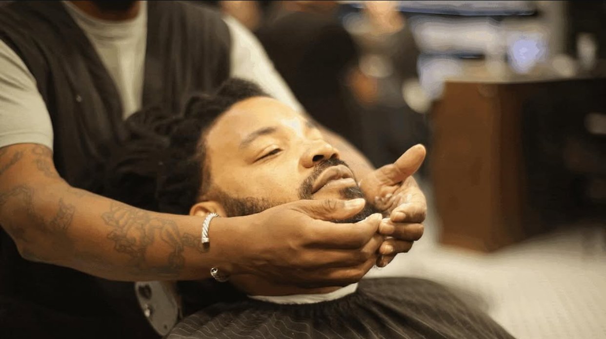 A man is getting a facial massage at a barbershop.