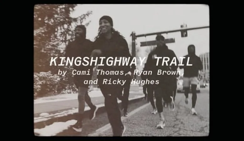 A group of people walking in a trail during winter, with snow on the ground and trees in the background. The photo is in black and white and features the text 'KINGSHIGHWAY TRAIL by Cami Thomas, Ryan Brown, and Ricky Hughes' overlayed.