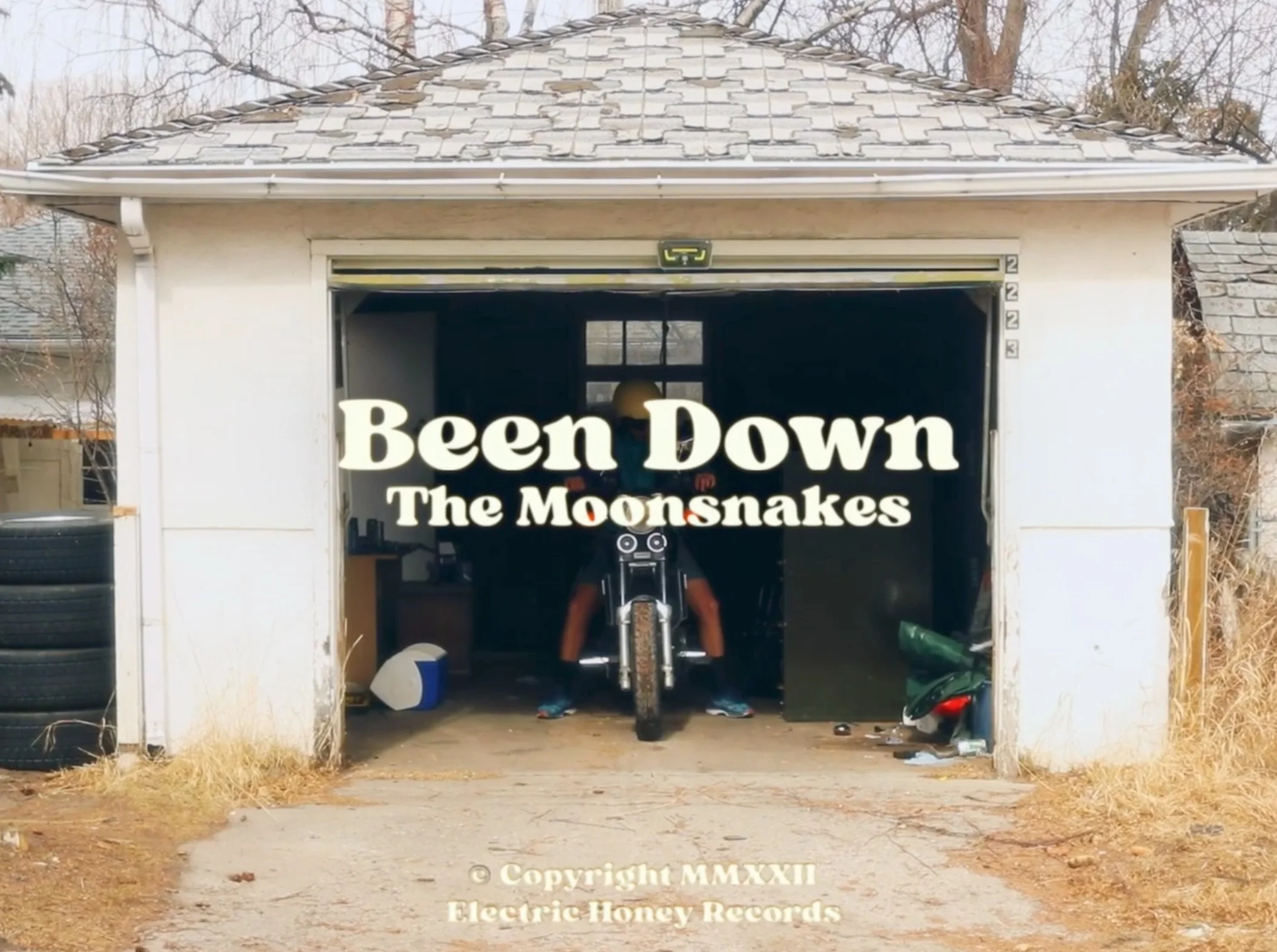 Text overlay on an image showing a garage with a person on a motorcycle inside, and the words "Been Down The Moonsnakes" and copyright information at the bottom.