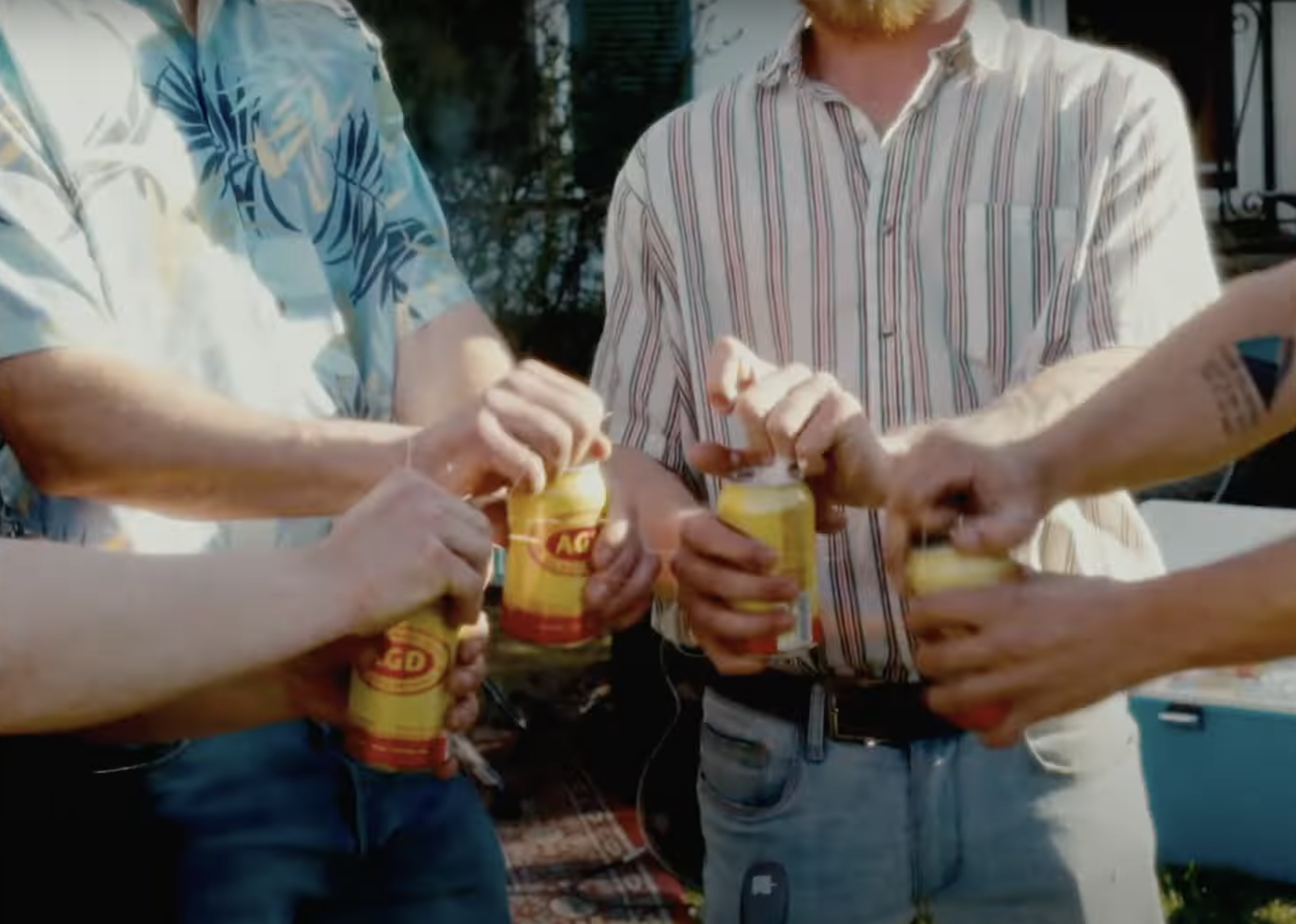 Four people holding open cans of food with their hands, preparing to eat outdoors.