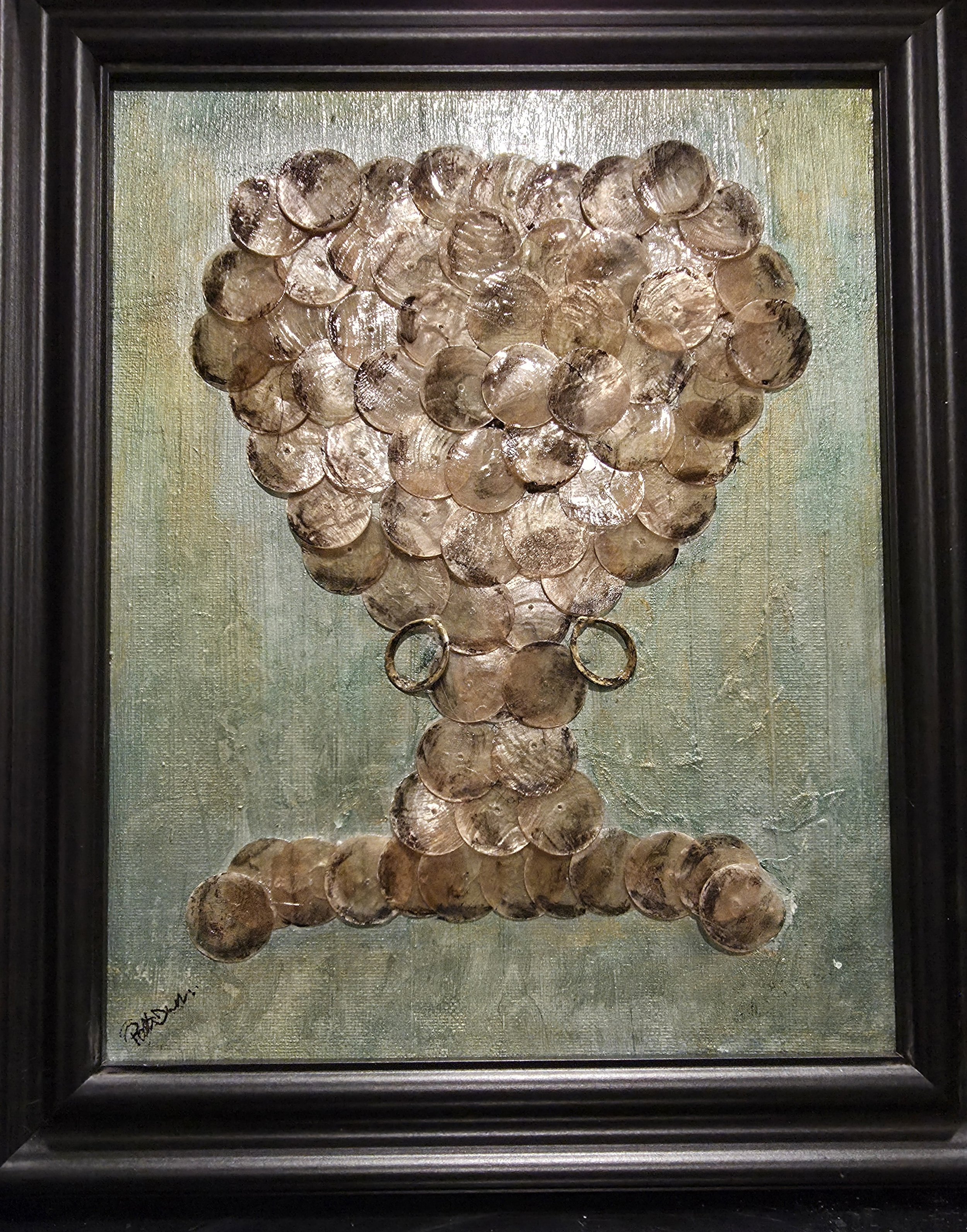 Framed artwork of the back of woman made from mother of pearl discs on a textured background.