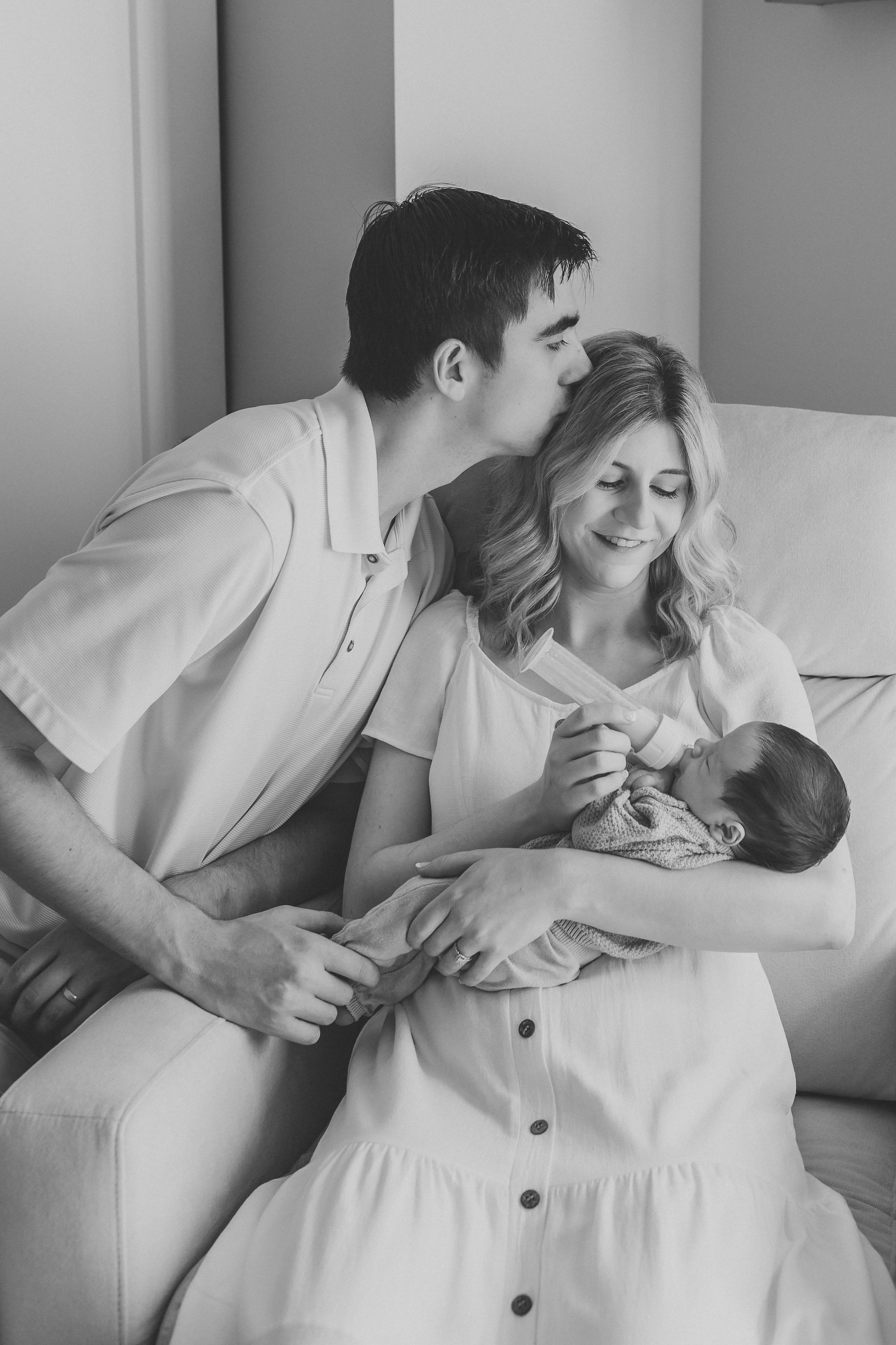 new parents in seattle home feeding their new baby during photo session