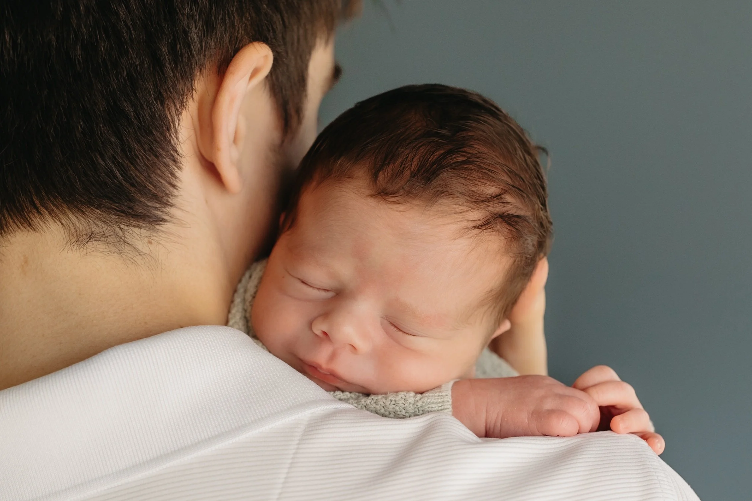 newborn baby boy resting on dad's shoulder during in-home session