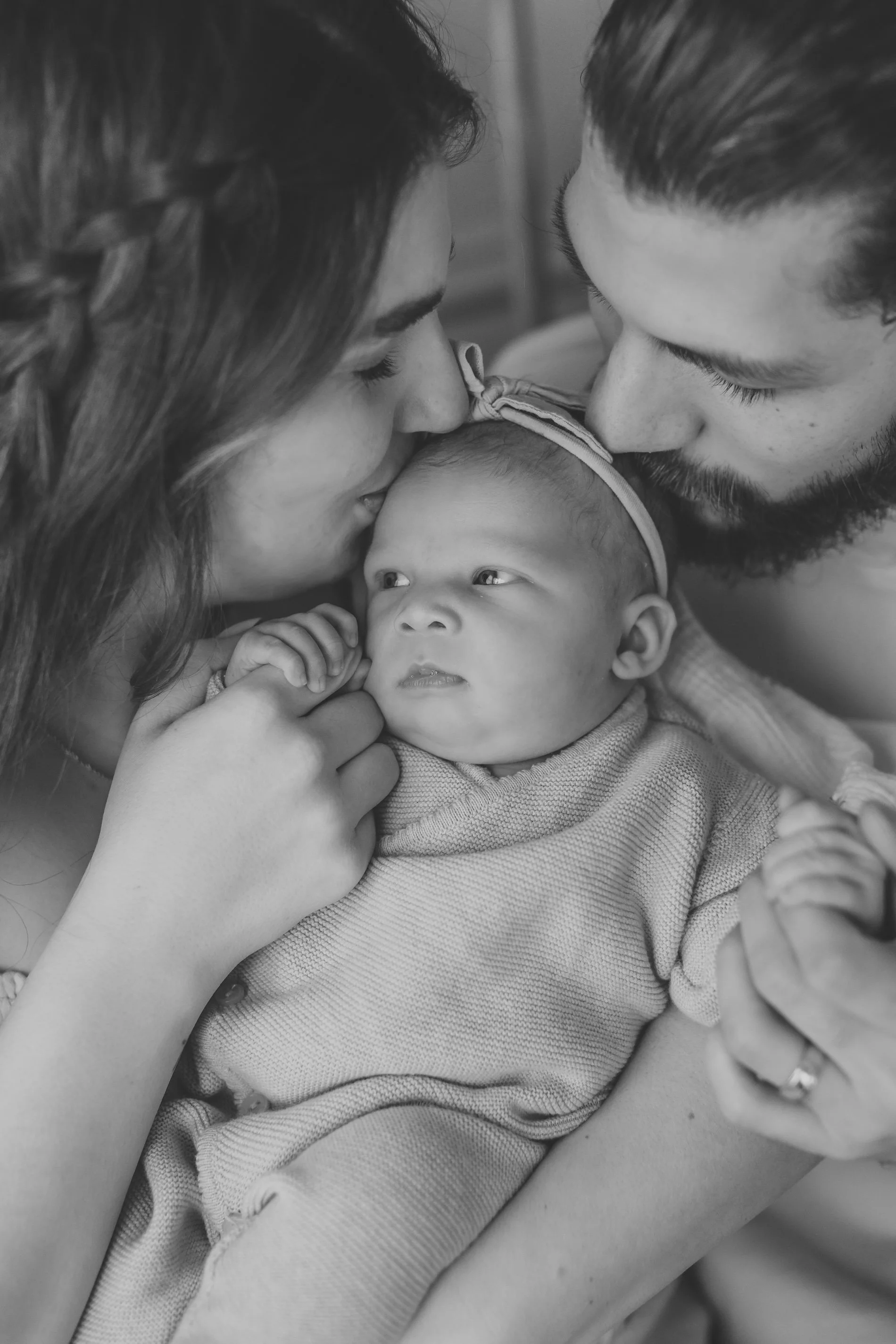 Up close image of Snohomish parents kissing newborn baby's cheeks