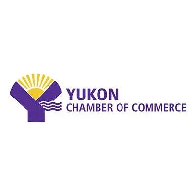Yukon Chamber of Commerce logo with a purple hand holding a yellow sun and waves.
