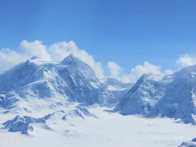 Snow-covered mountains under a partly cloudy sky.