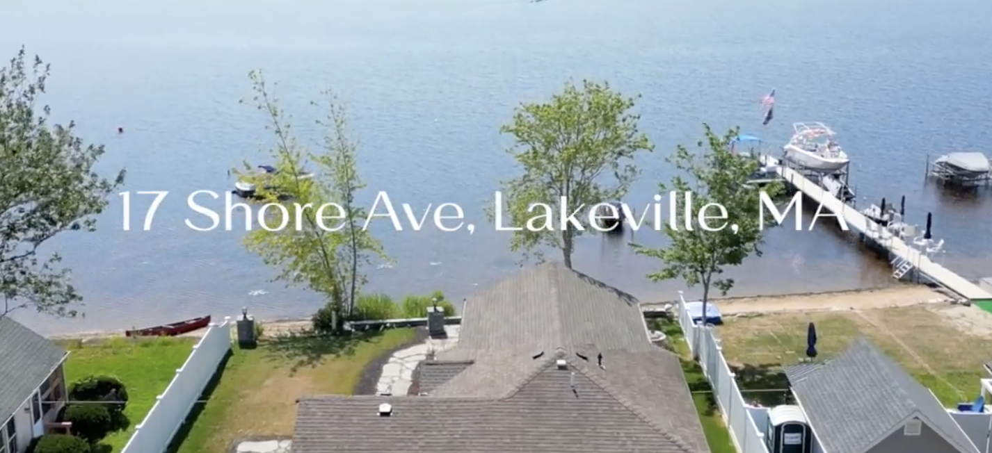 Aerial view of a lakeside property with a dock, boats, trees, and houses at 17 Shore Ave, Lakeville, MA.