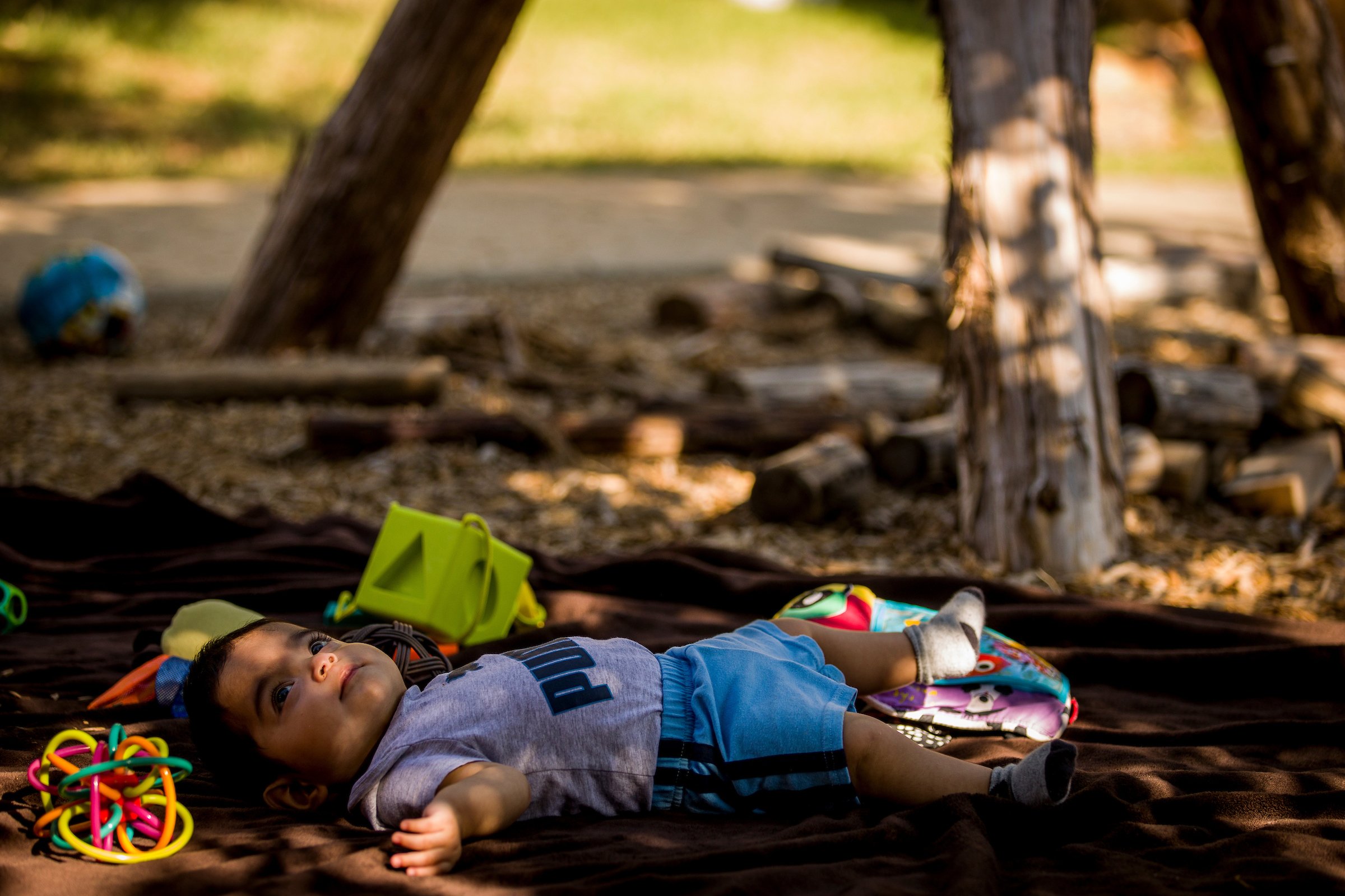 infant boy laying down under a safe, shaded area in a nature classroom