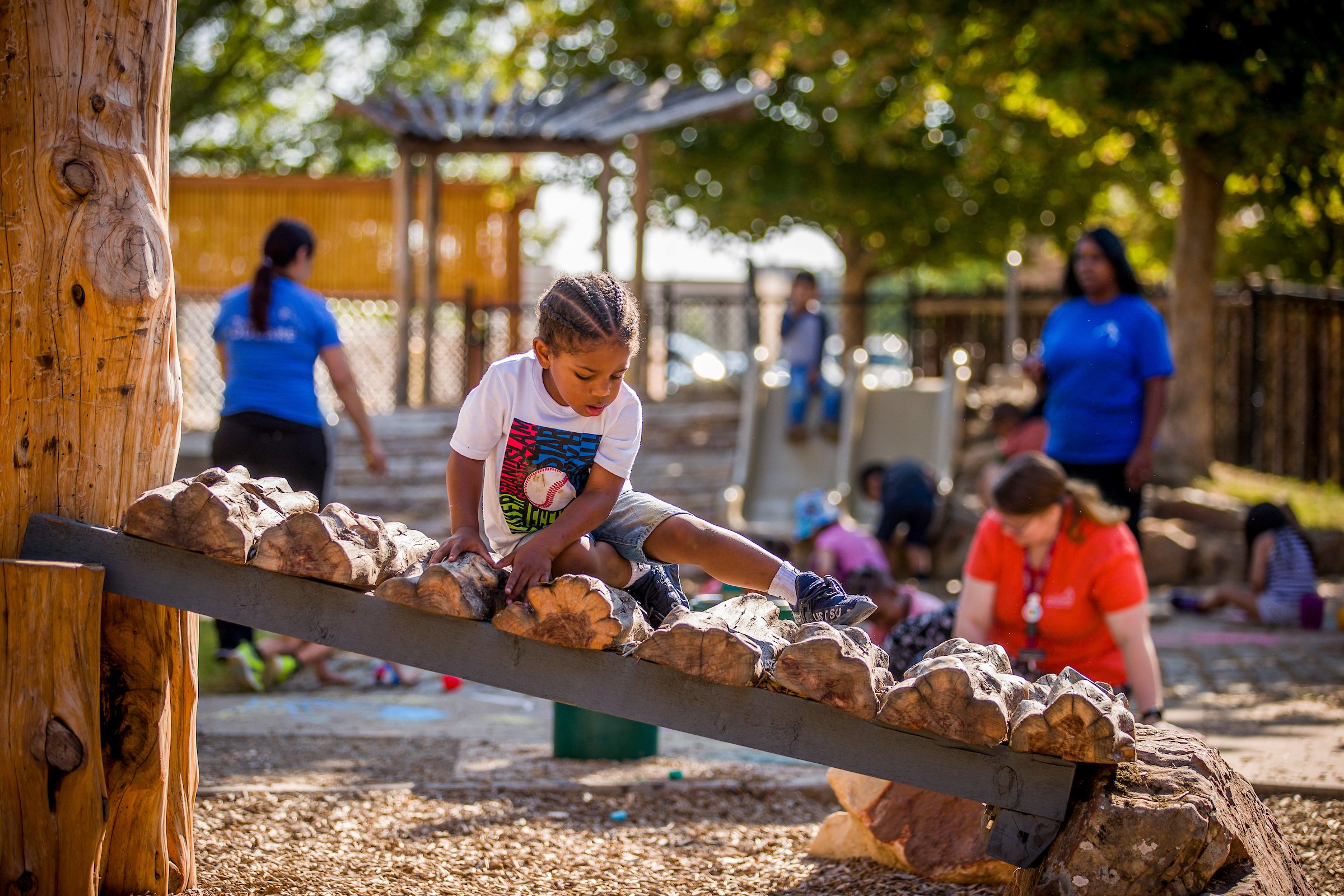 young boy climbing on a slanted section of logs in a nature classroom