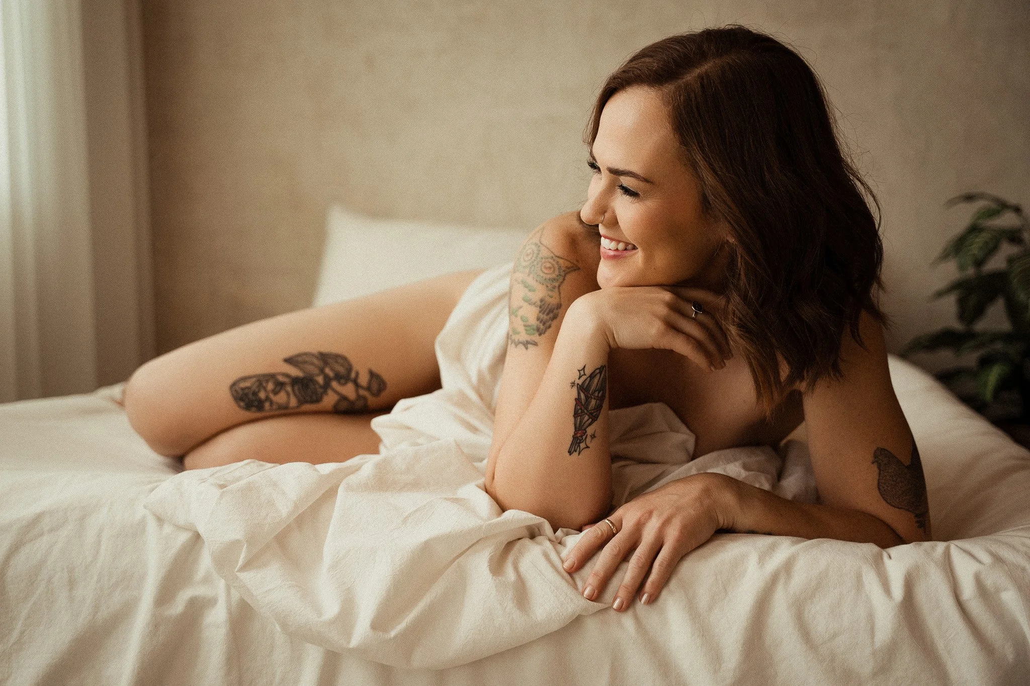 glowing tattoo'd woman in a luxury boudoir studio in round rock texas with an all female photographer and team.