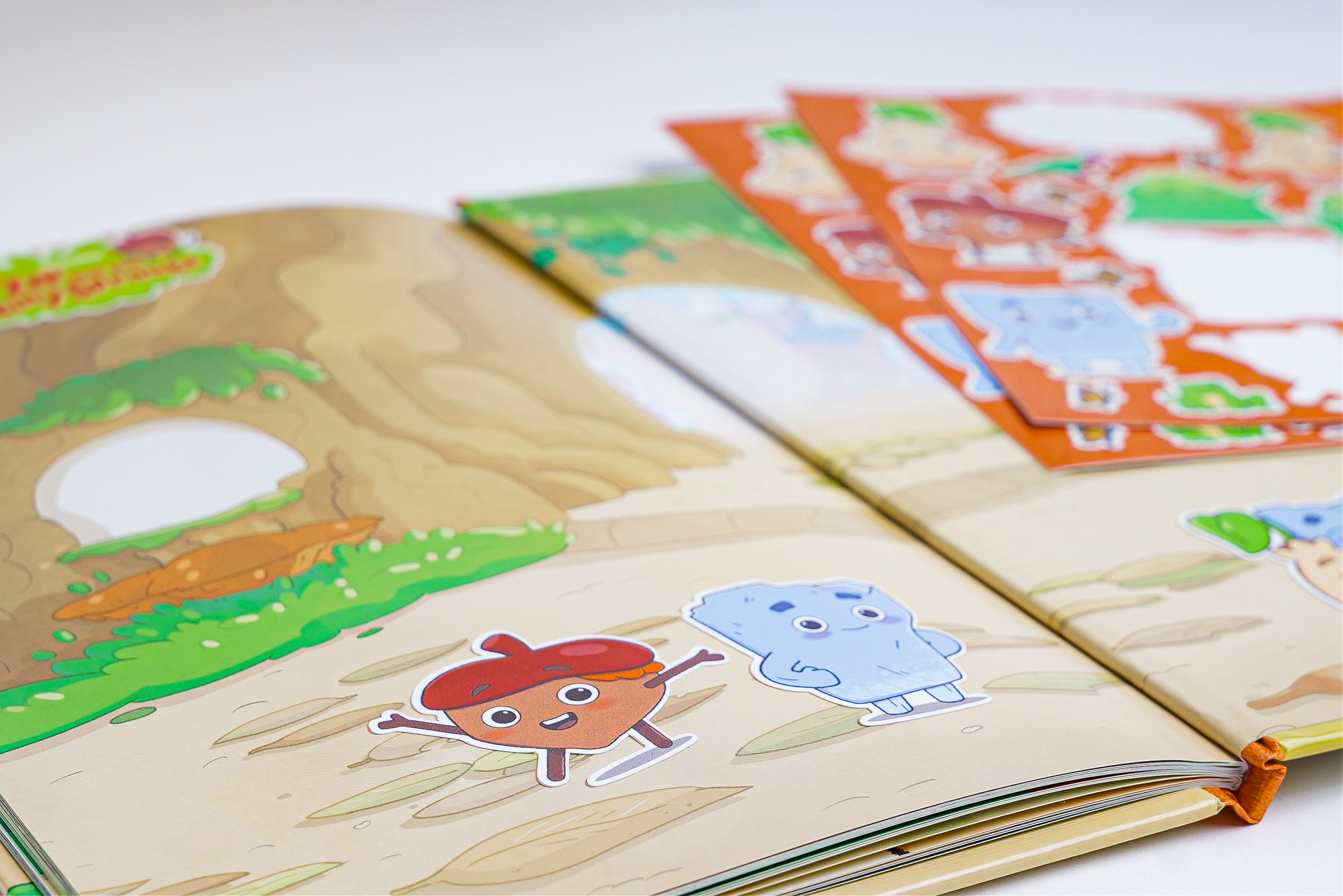 Open children's book with cartoon characters of a tree stump and a blue rock, and colorful stickers of animals in the background.