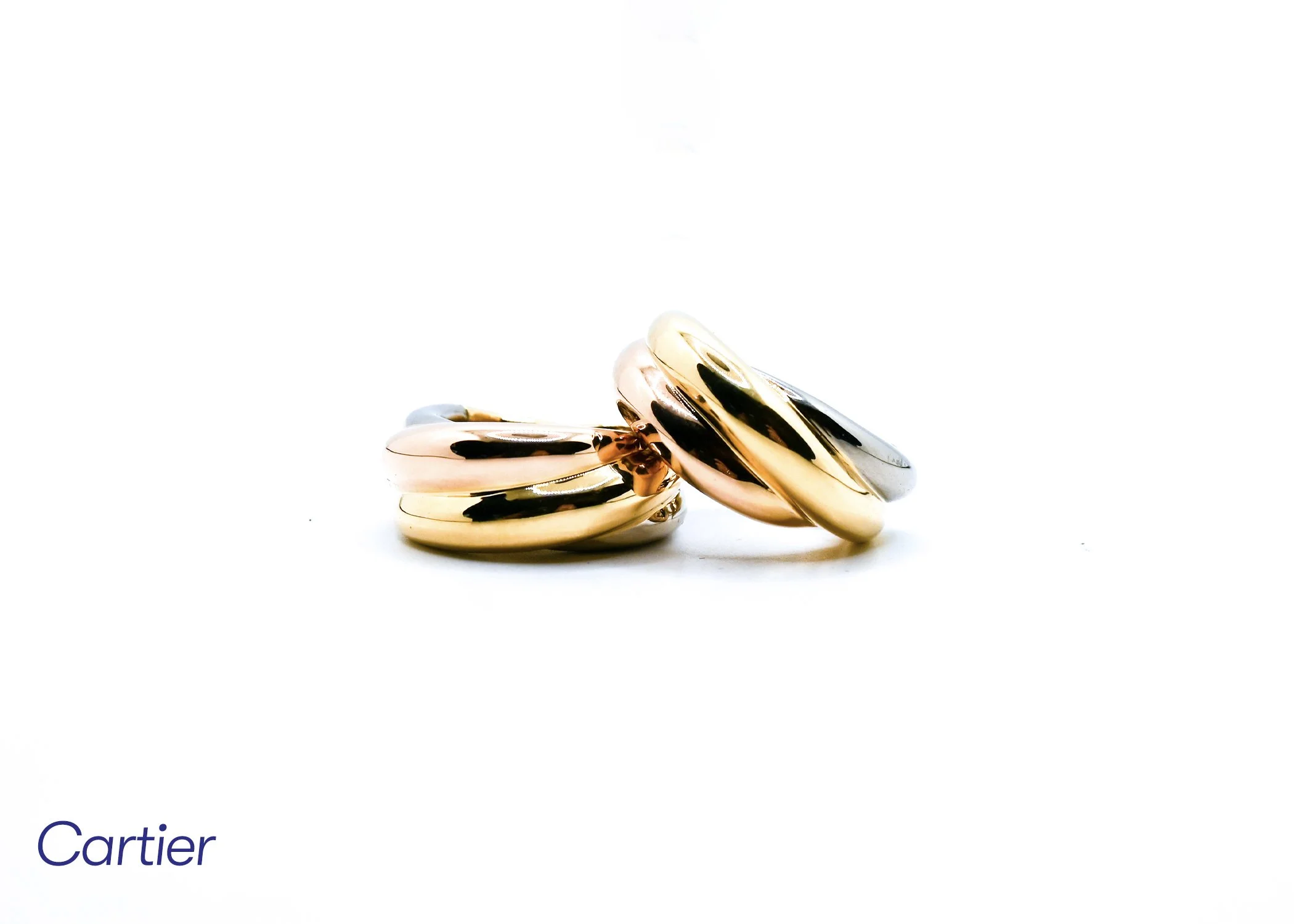 A stack of three gold, silver, and rose gold rings with a polished finish, arranged on a white surface against a white background.
