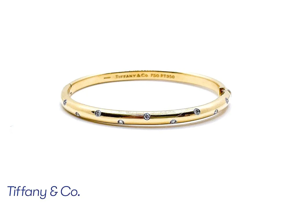 A gold Tiffany & Co. bracelet adorned with small, evenly spaced diamonds on a white background.