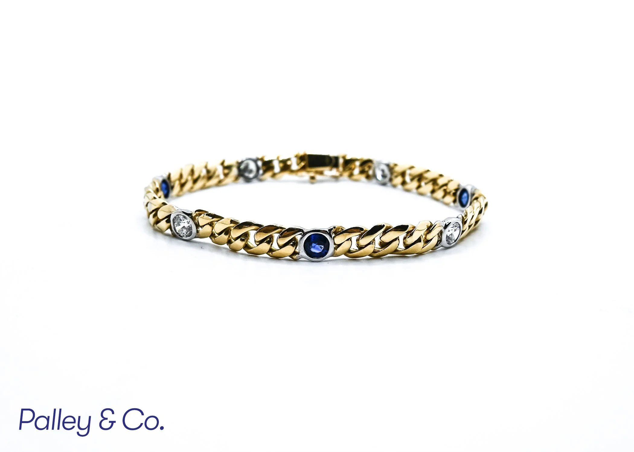 A gold bracelet with embedded diamonds and blue gemstones on a white background.