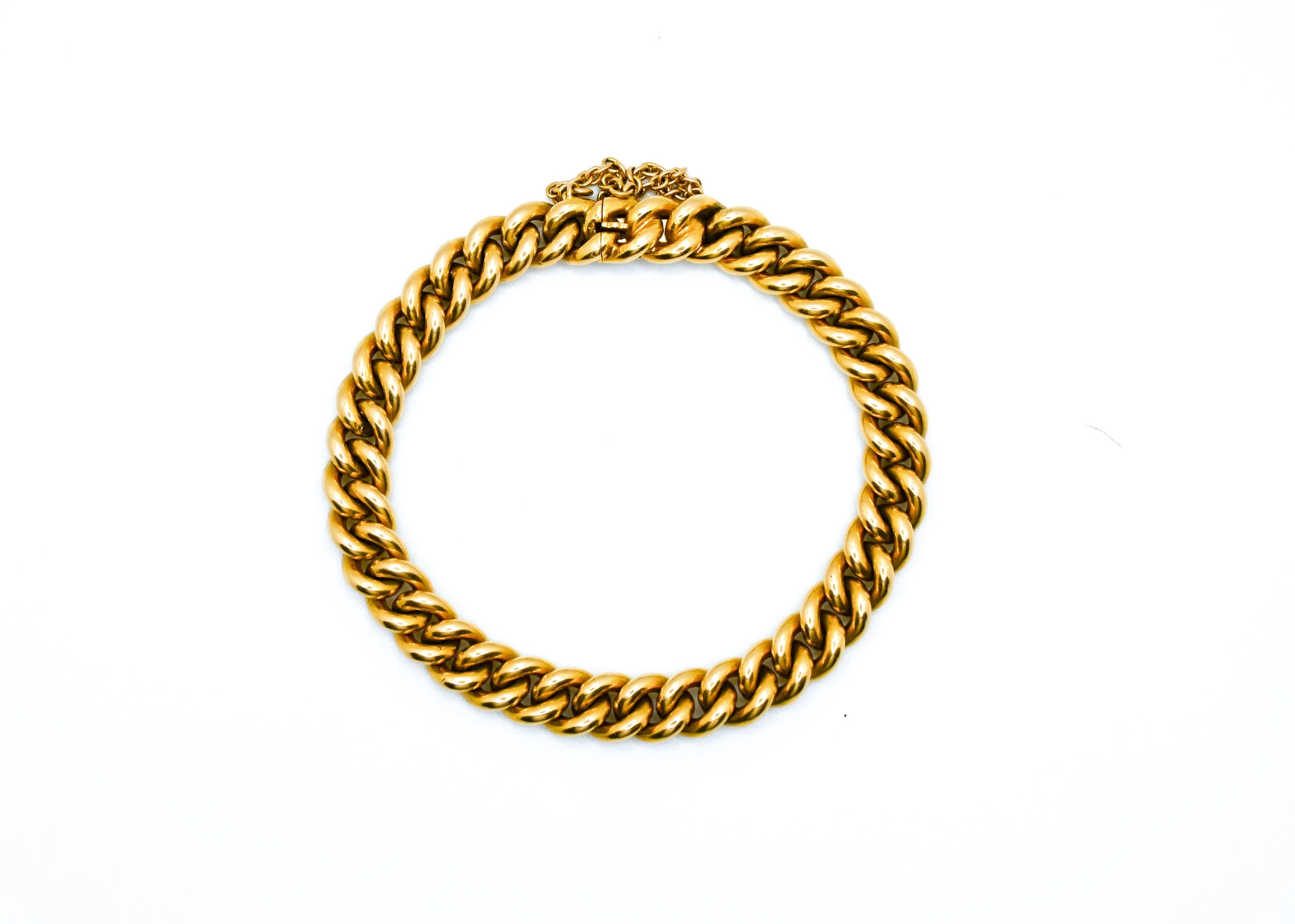 Gold twisted chain necklace forming a partial circle on a white background.