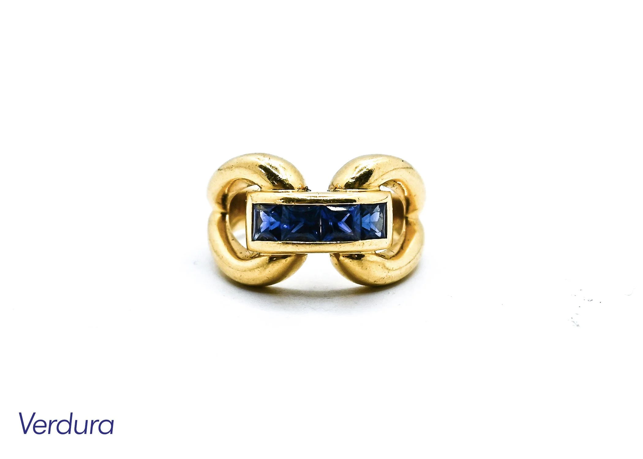 A gold ring with a rectangular deep blue gemstone in the center, positioned against a plain white background.