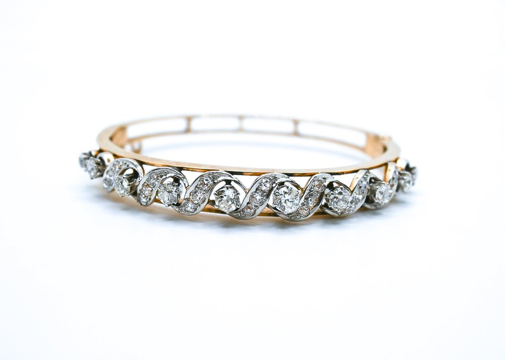 A gold and silver ring with a pattern of diamonds set in a wave design.