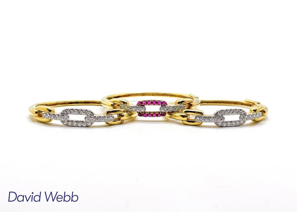 A set of gold and silver jewelry bracelets with diamonds and pink gemstones, arranged in a row on a plain white background.