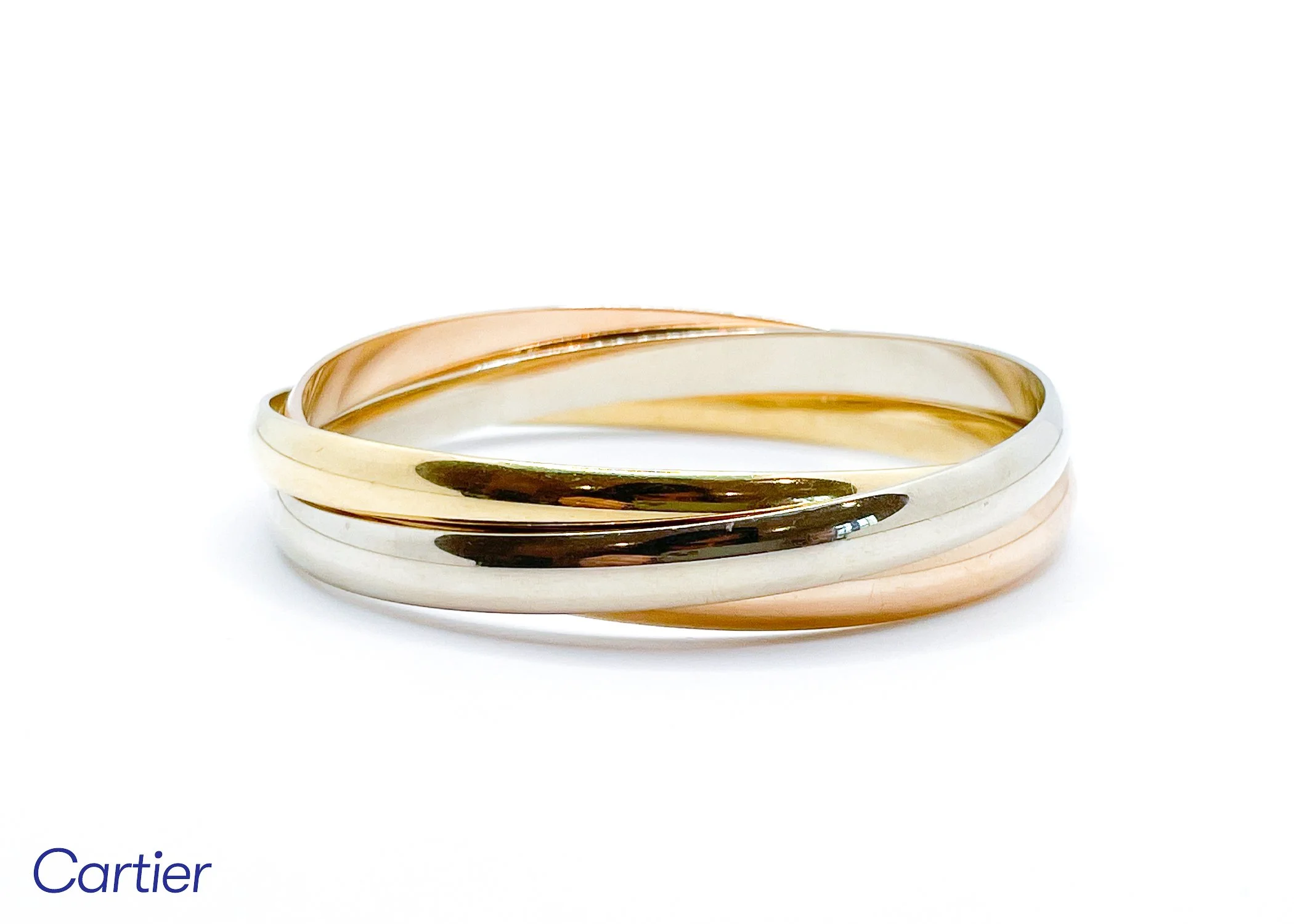 Close-up of layered Cartier ring, gold and silver, on white background.