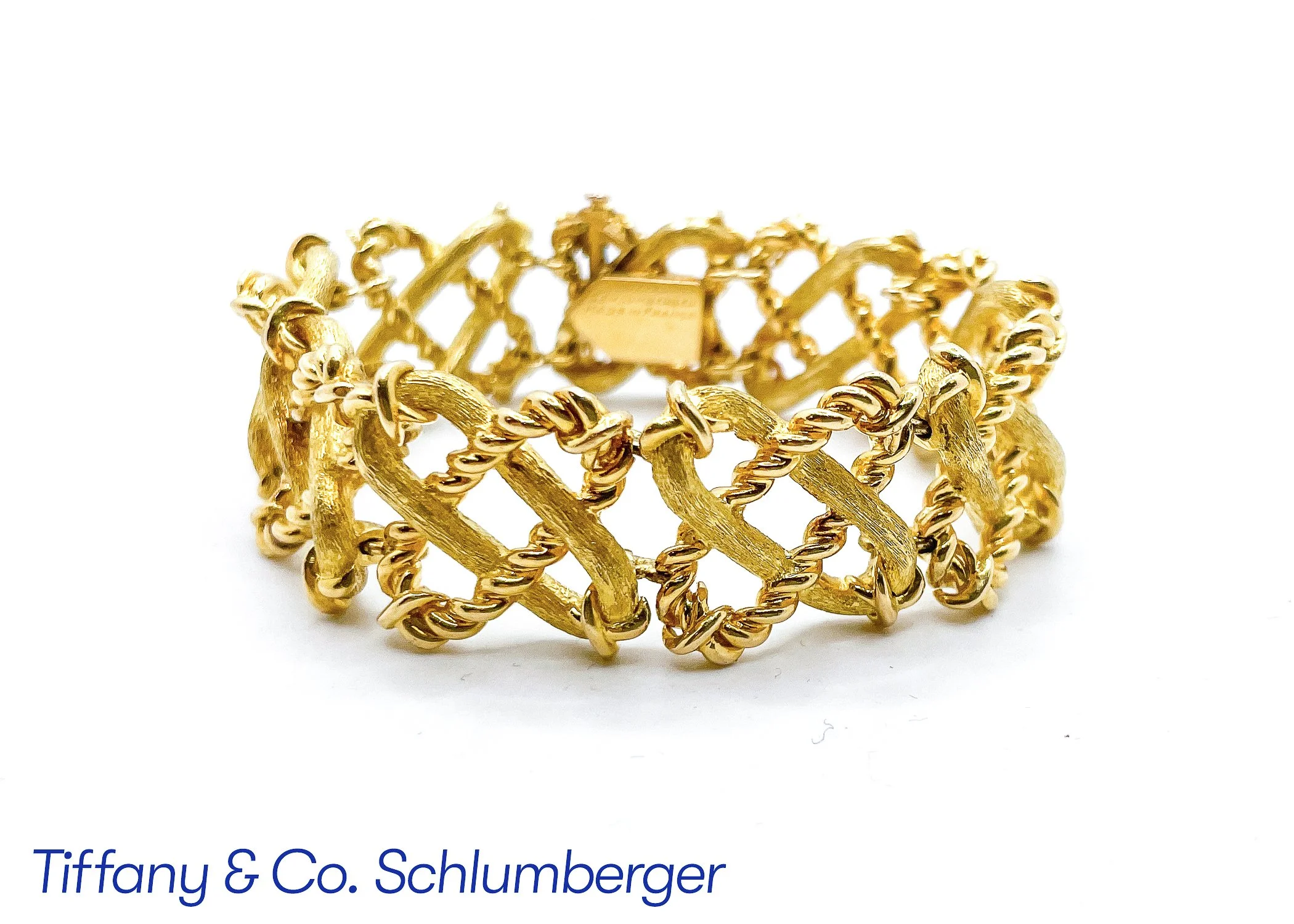 A gold-colored chain bracelet with a linked, textured design, resting on a white background with text below reading 'Tiffany & Co. Schlumberger'.