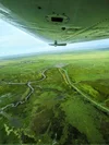Aerial view of a green wetlands landscape with winding rivers, taken from an aircraft.