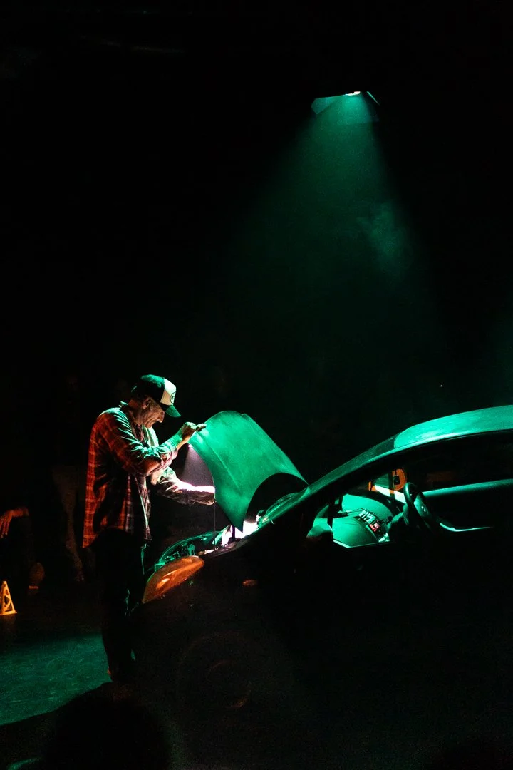 Man looking into car bonet on a stage