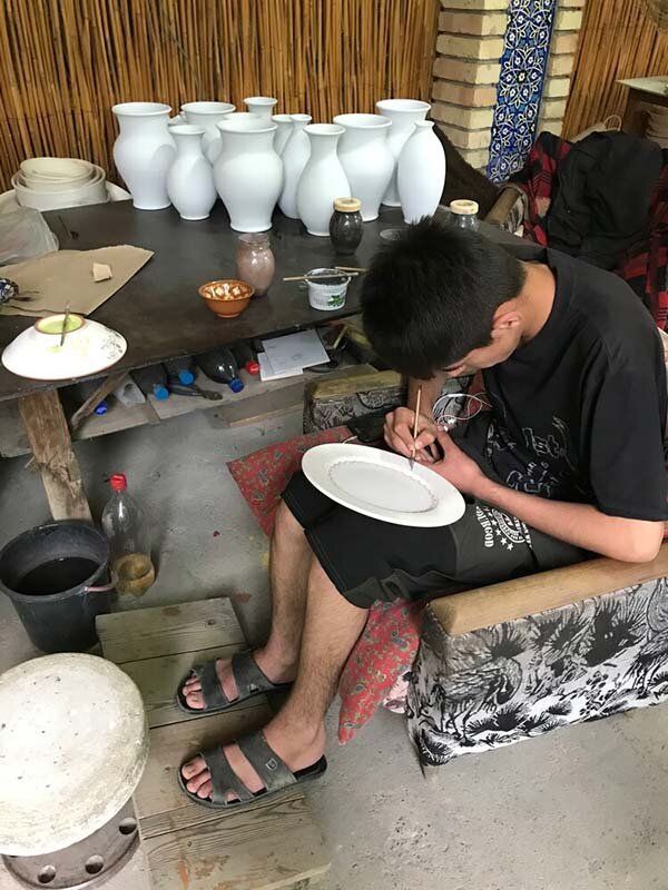 Student painting vases at Rustam Uzmanov workshop, Rishtan