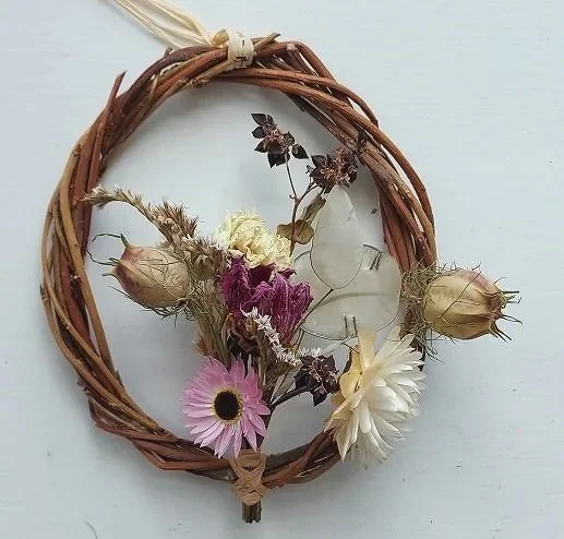 Small dried flower wreath with meadow look with pink and white flowers.