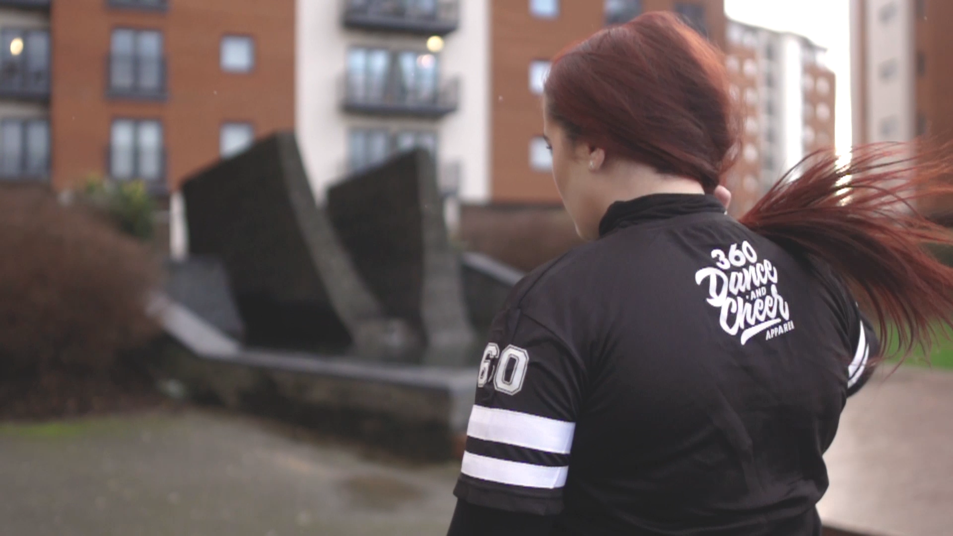 young woman flips hair revealing sports brand logo on back of jersey