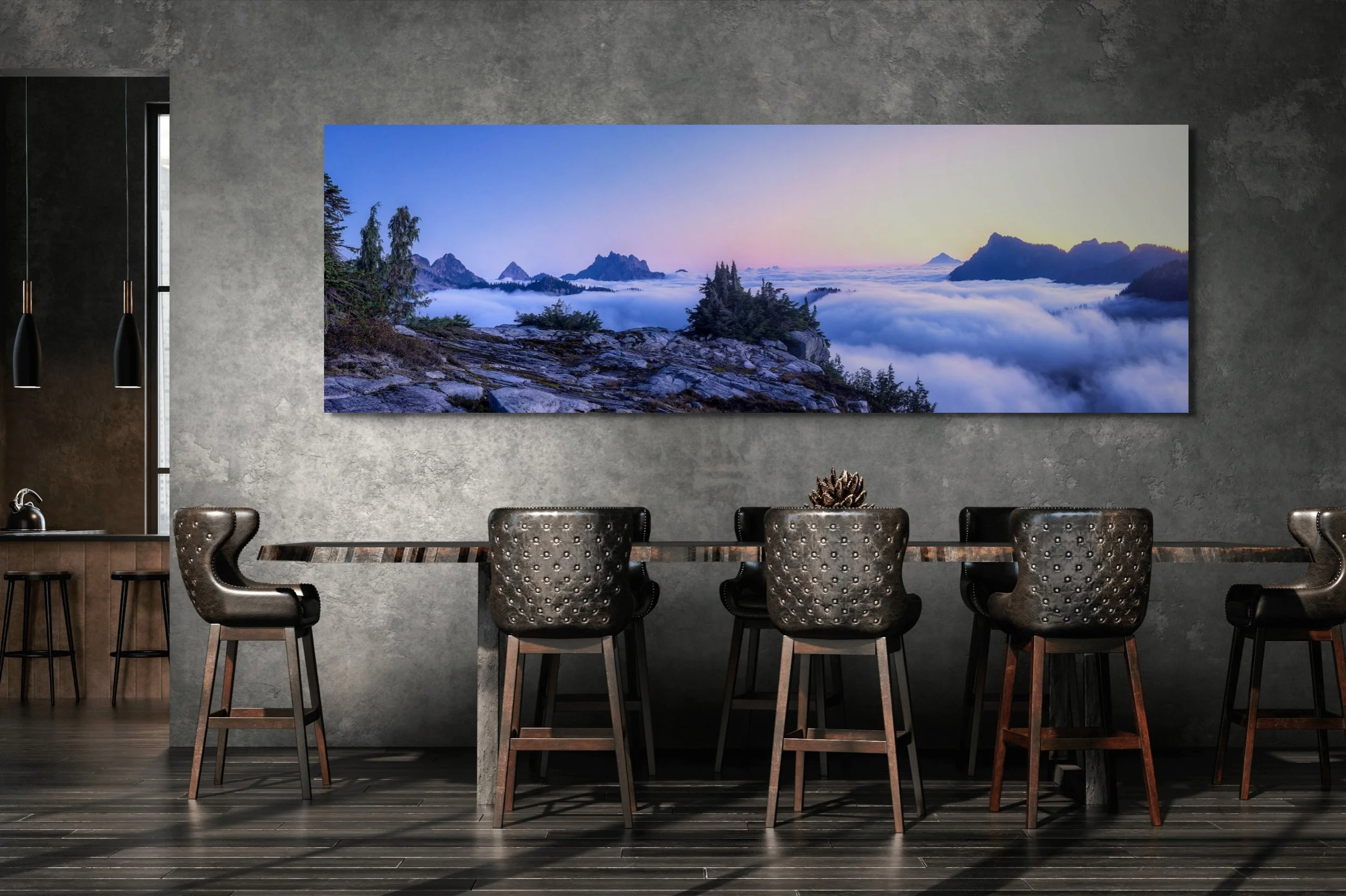 Modern dining room with a long table and black leather chairs, a large landscape painting of mountains and clouds on the wall, and dark wood flooring.