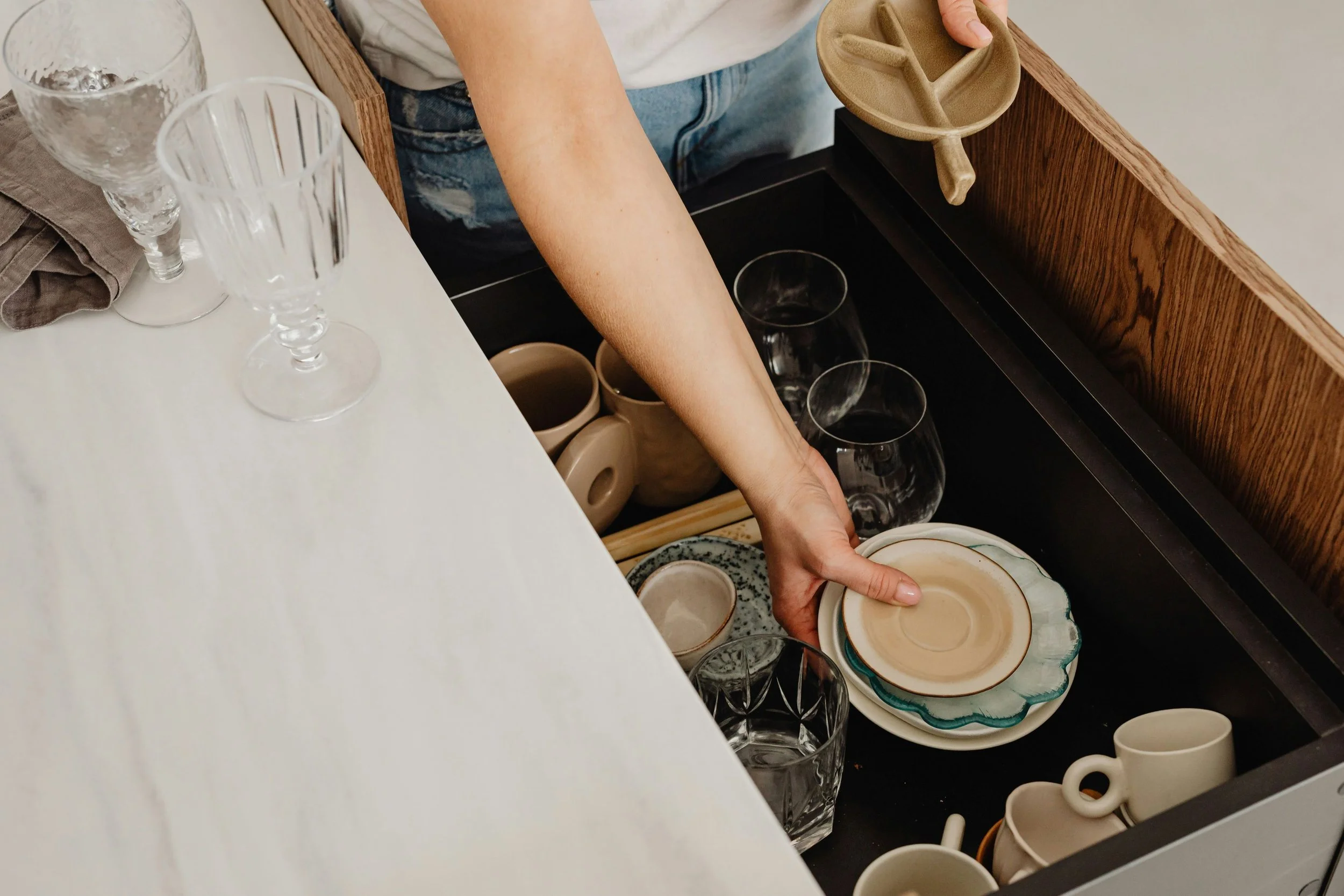 woman pulling misc dishes out of a drawer to declutter and pack them