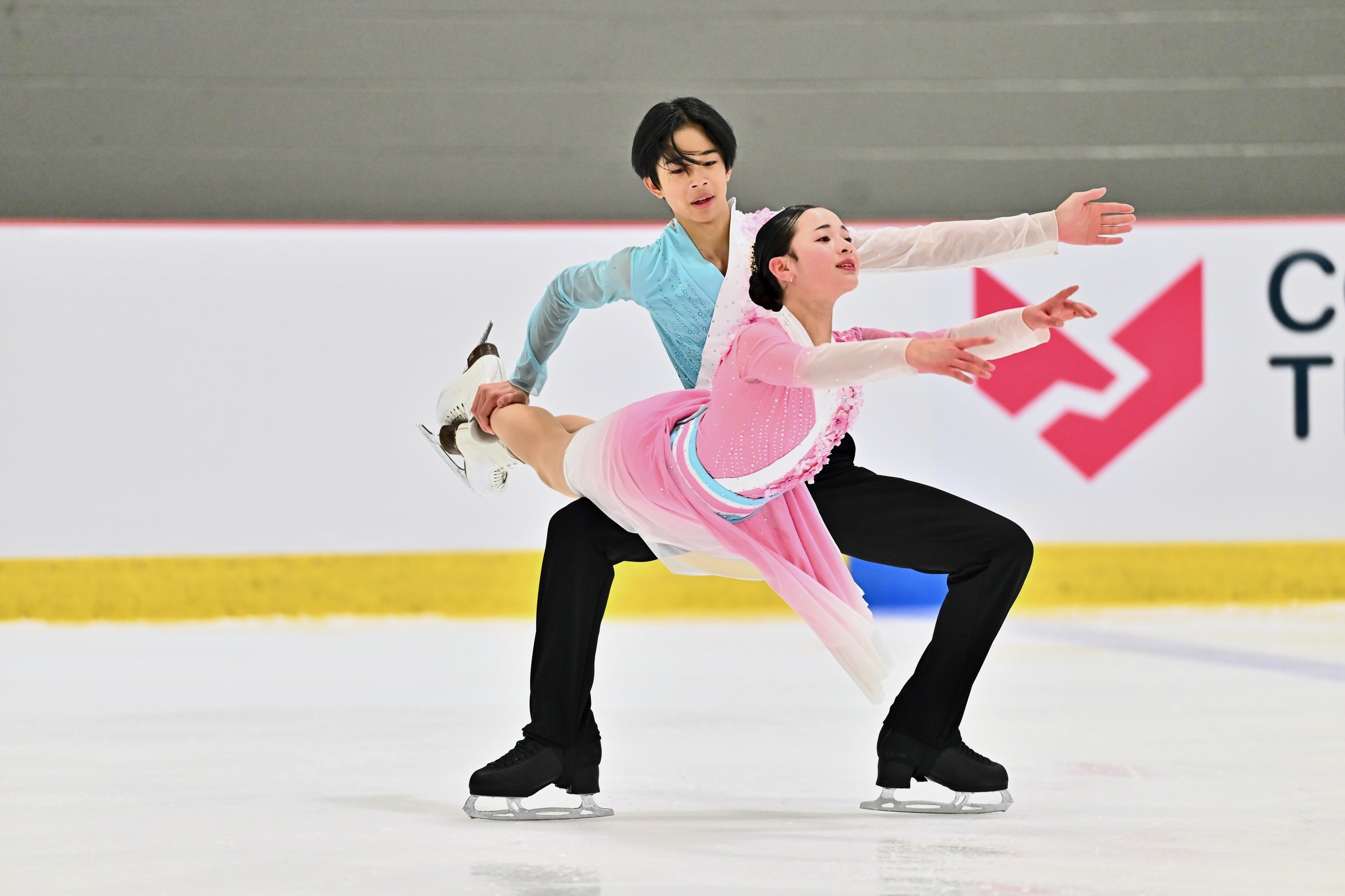 A male and female figure skaters performing a synchronized routine on the ice rink.