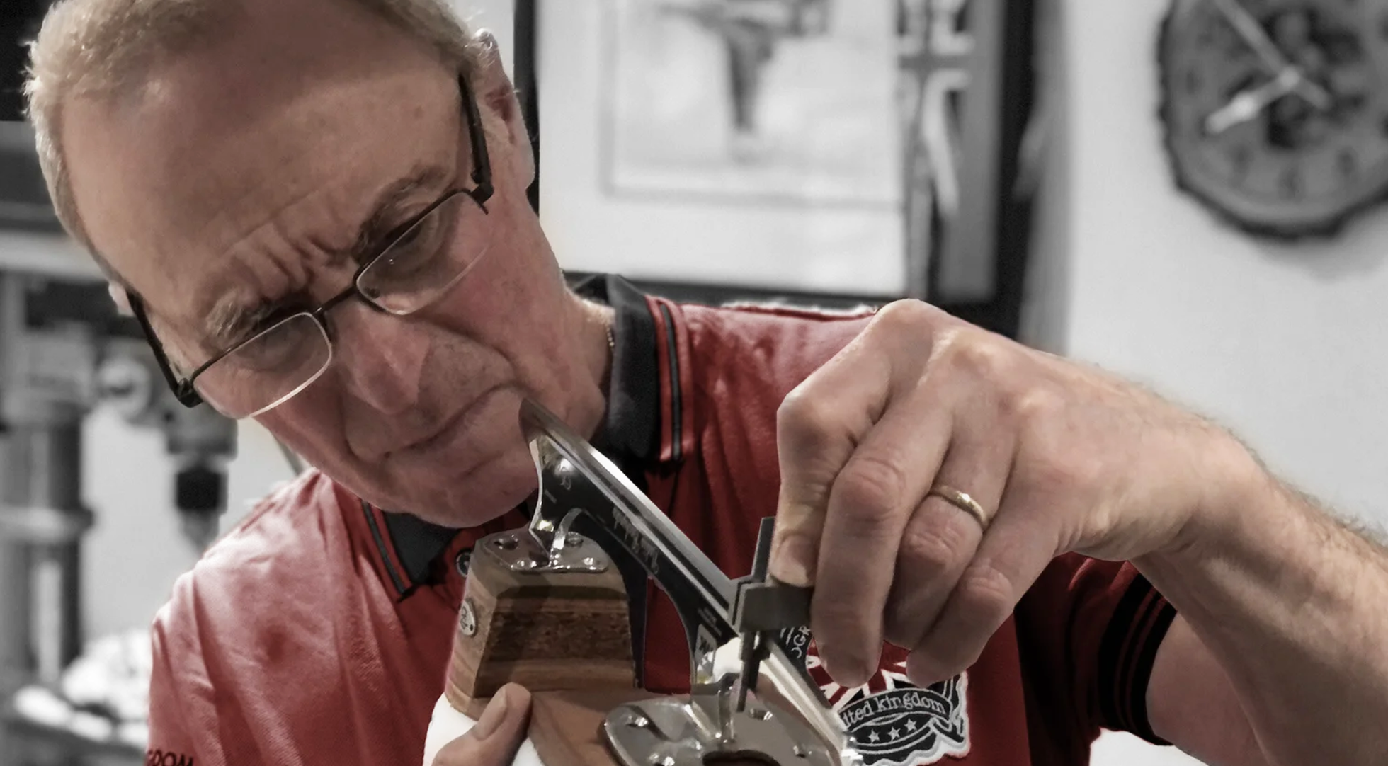 An older man with glasses working on a woodworking project in a workshop.
