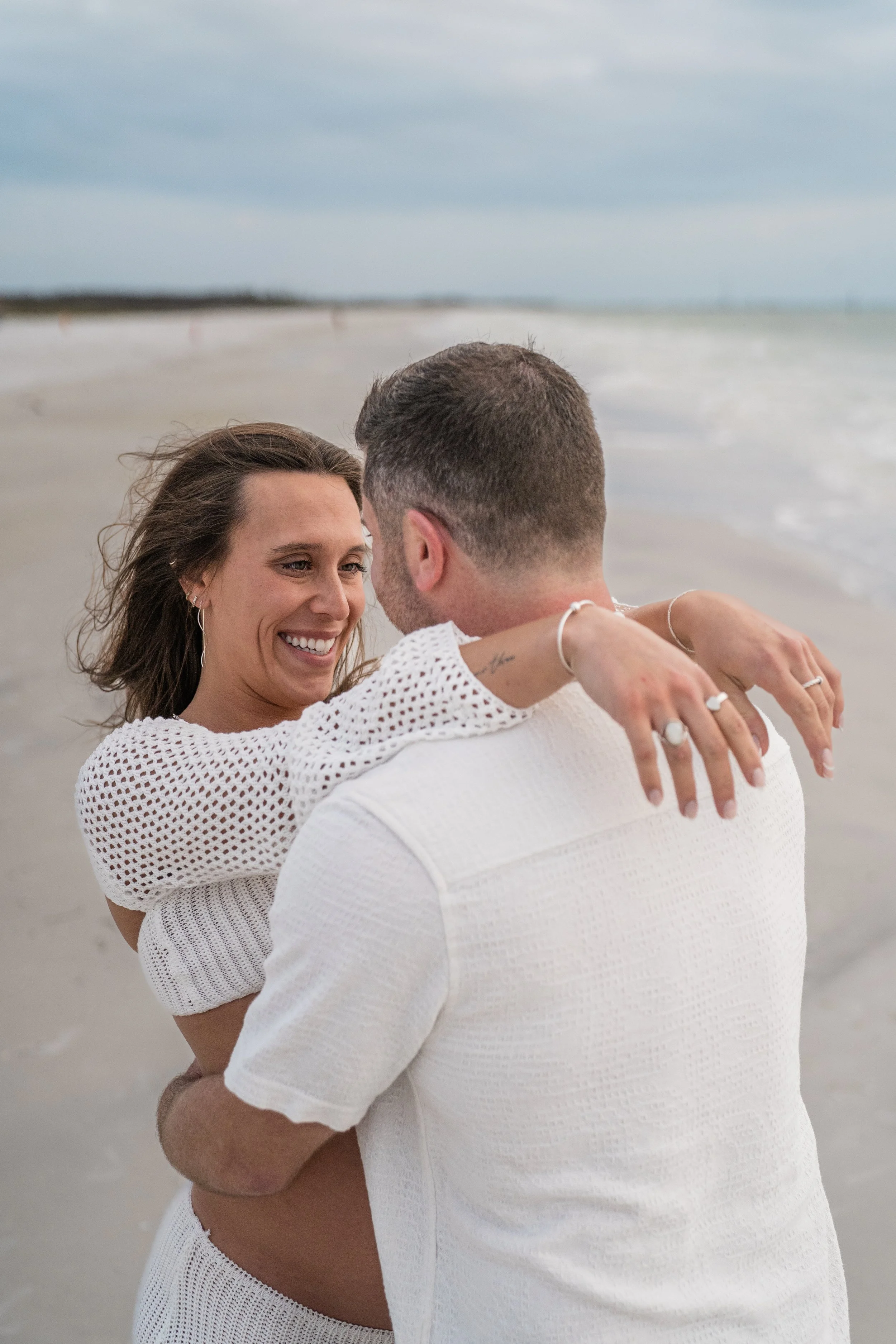 A couple embracing on a beach, smiling at each other.