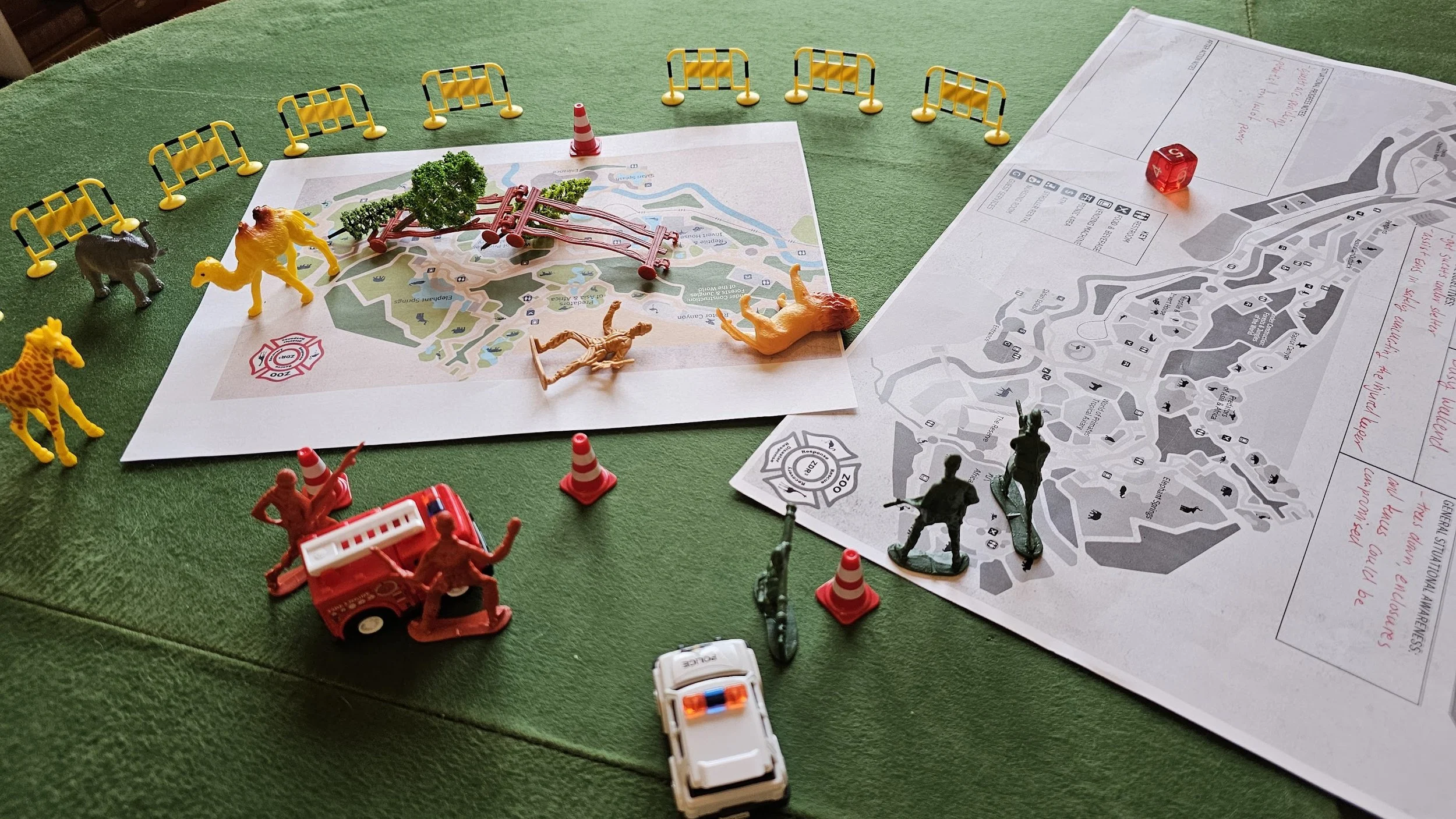 A photo of a tabletop exercise, with zoo maps and little toy figurines scattered across them