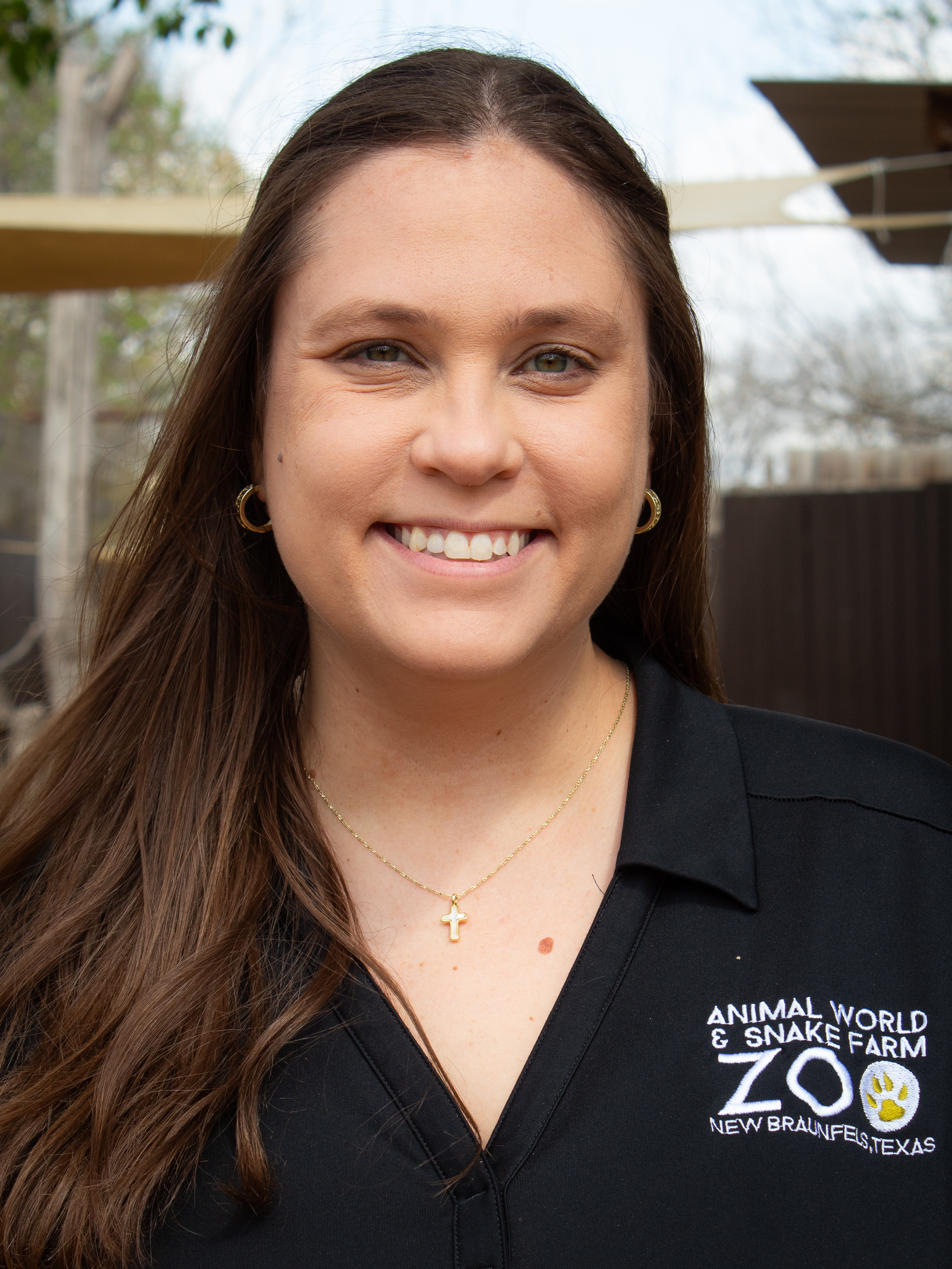 A white woman with long, straight brown hair smiles into the camera