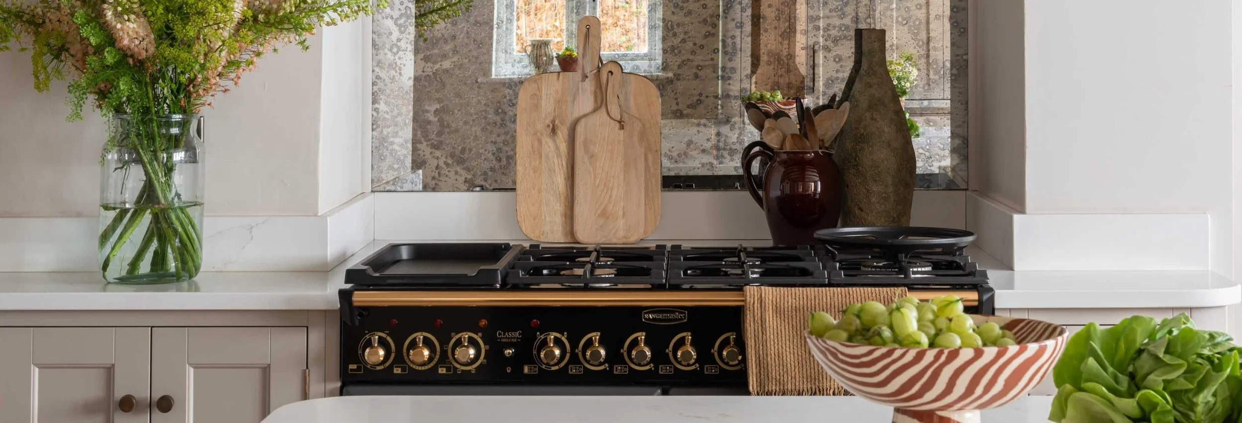Classic range cooker with stone splashback and neutral kitchen cabinetry