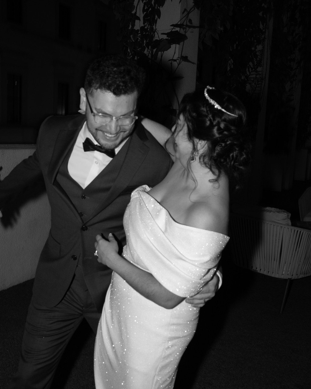 A couple, dressed in formal wedding attire, dancing closely and smiling at each other in a joyful moment at their wedding reception.