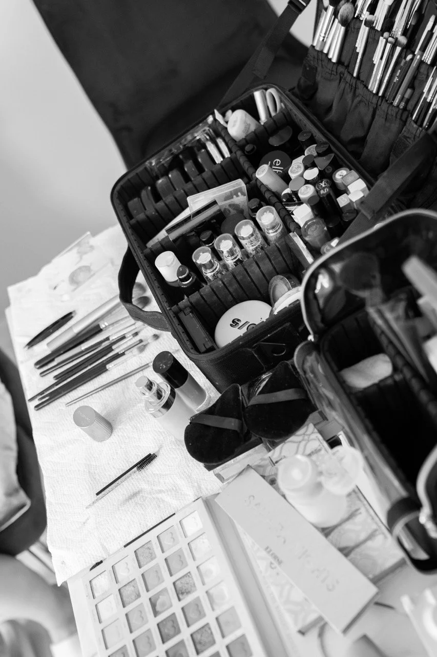 A table with various makeup tools and products, including brushes, bottles, and palettes, along with makeup cases and organized compartments.