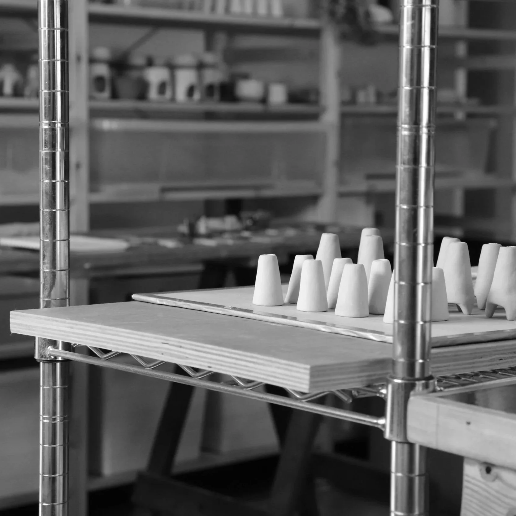 Mini handmade ceramic vases arranged in a pottery studio on a wooden board.
