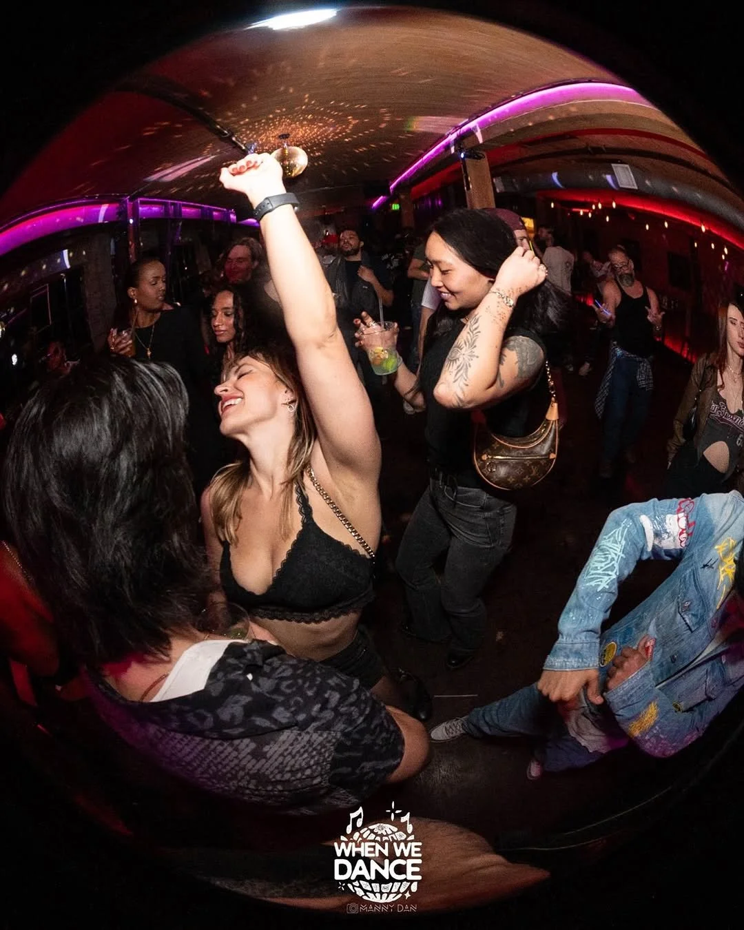 People dancing and socializing at a lively, colorful nightclub or party with dim lighting and neon accents.