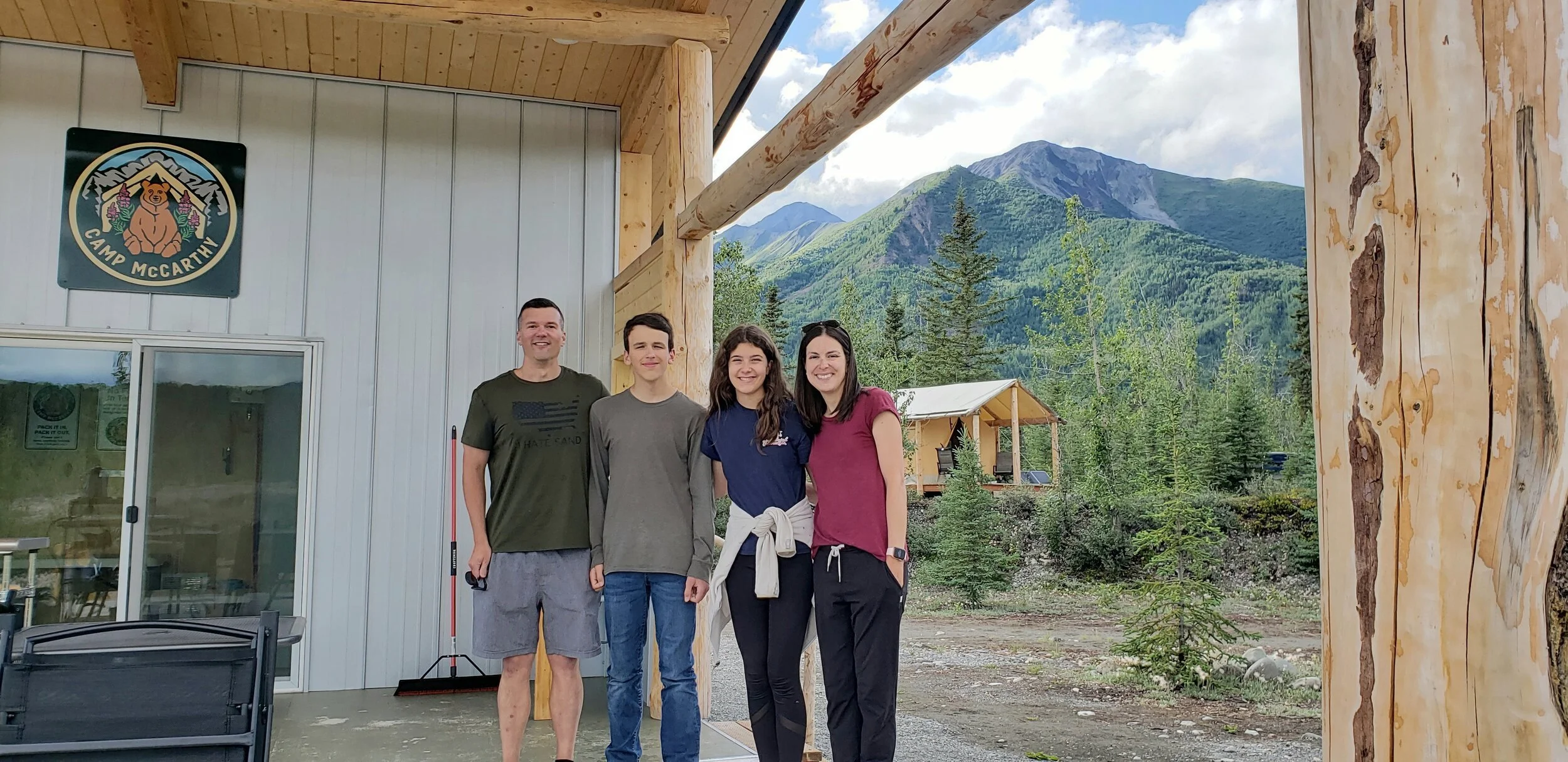 A family stand on the deck of the Paviion with Dryas Camp in the background