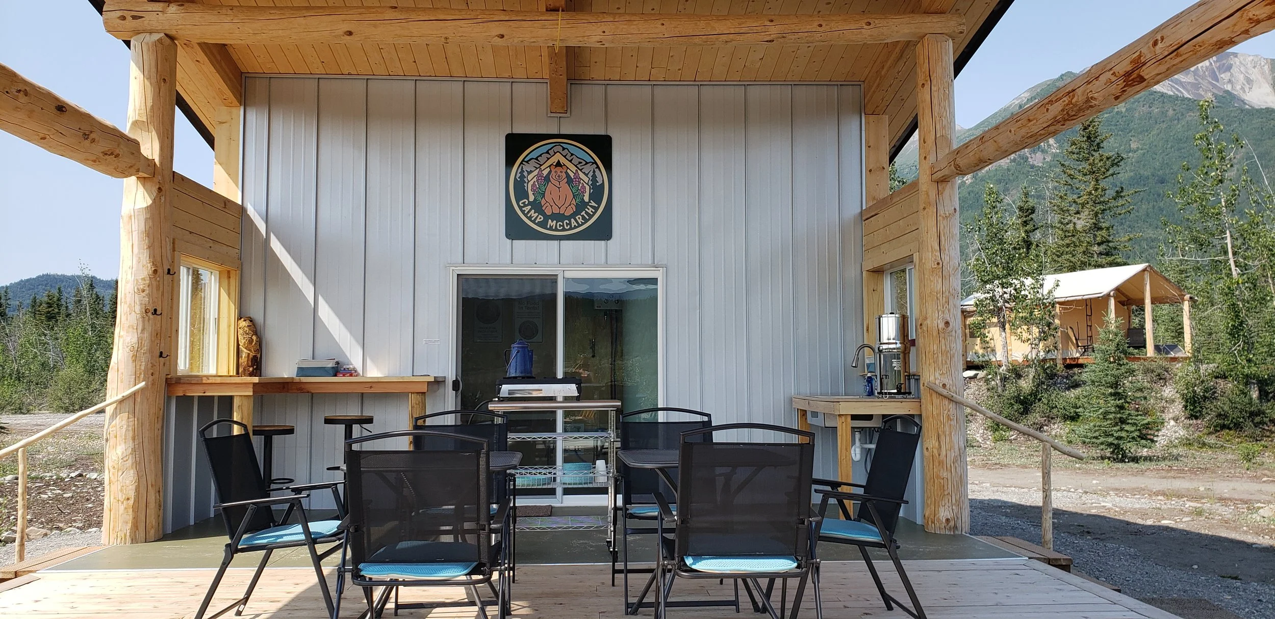 Camp McCarthy's Pavilion deck with cafe tables and chairs, food storage, sinks, and coffee and tea station.