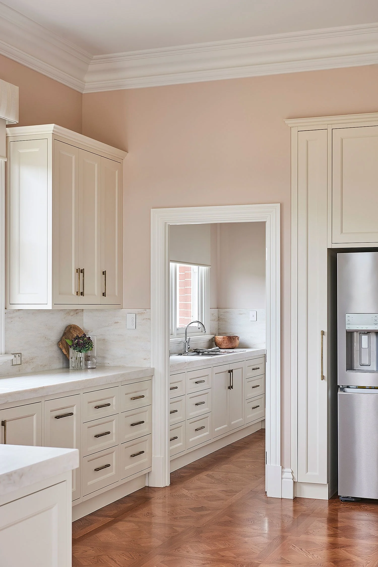 A modern kitchen with white cabinetry, a window above the sink, and hardwood floors.