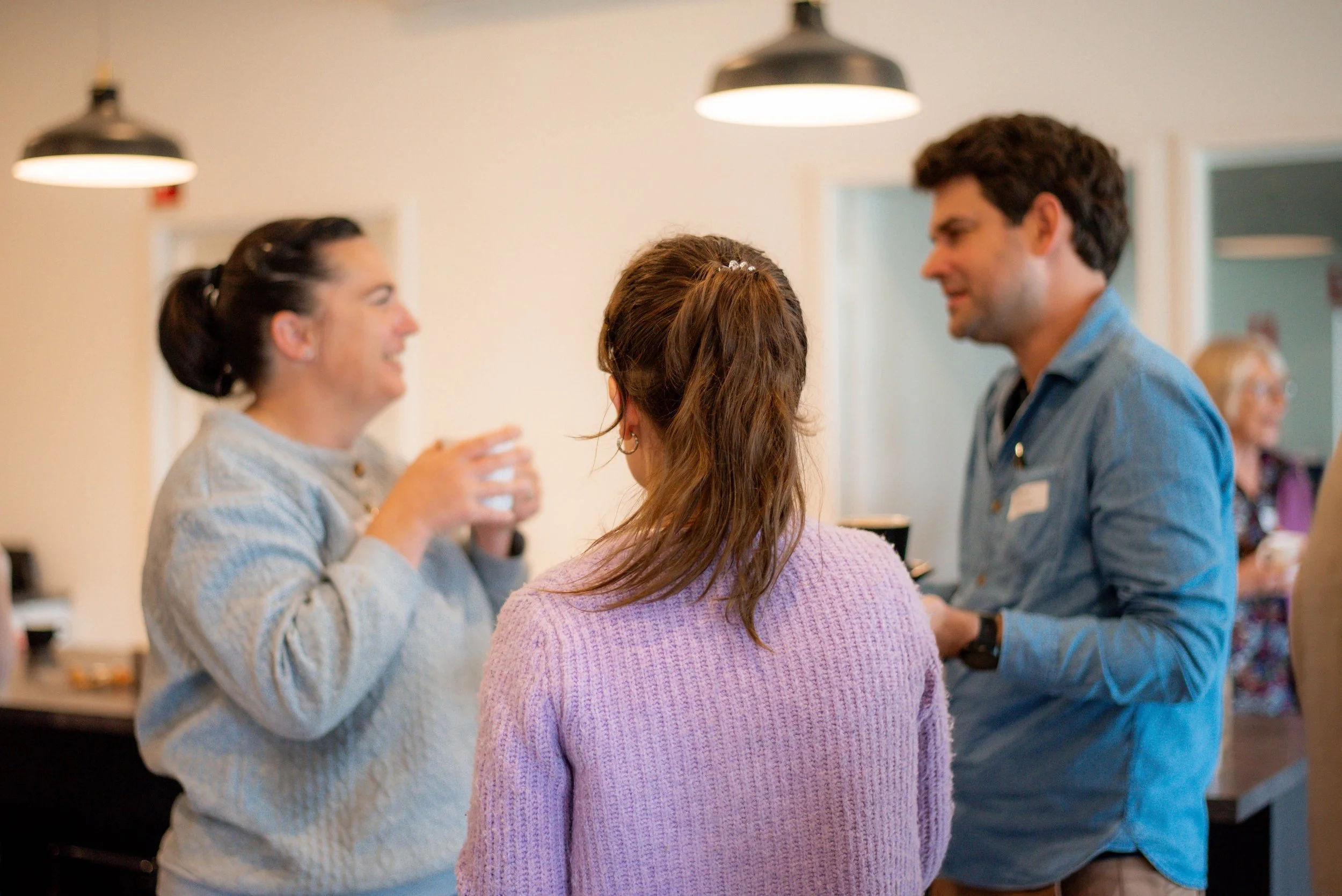 Two women and one man casually chatting in a small group.