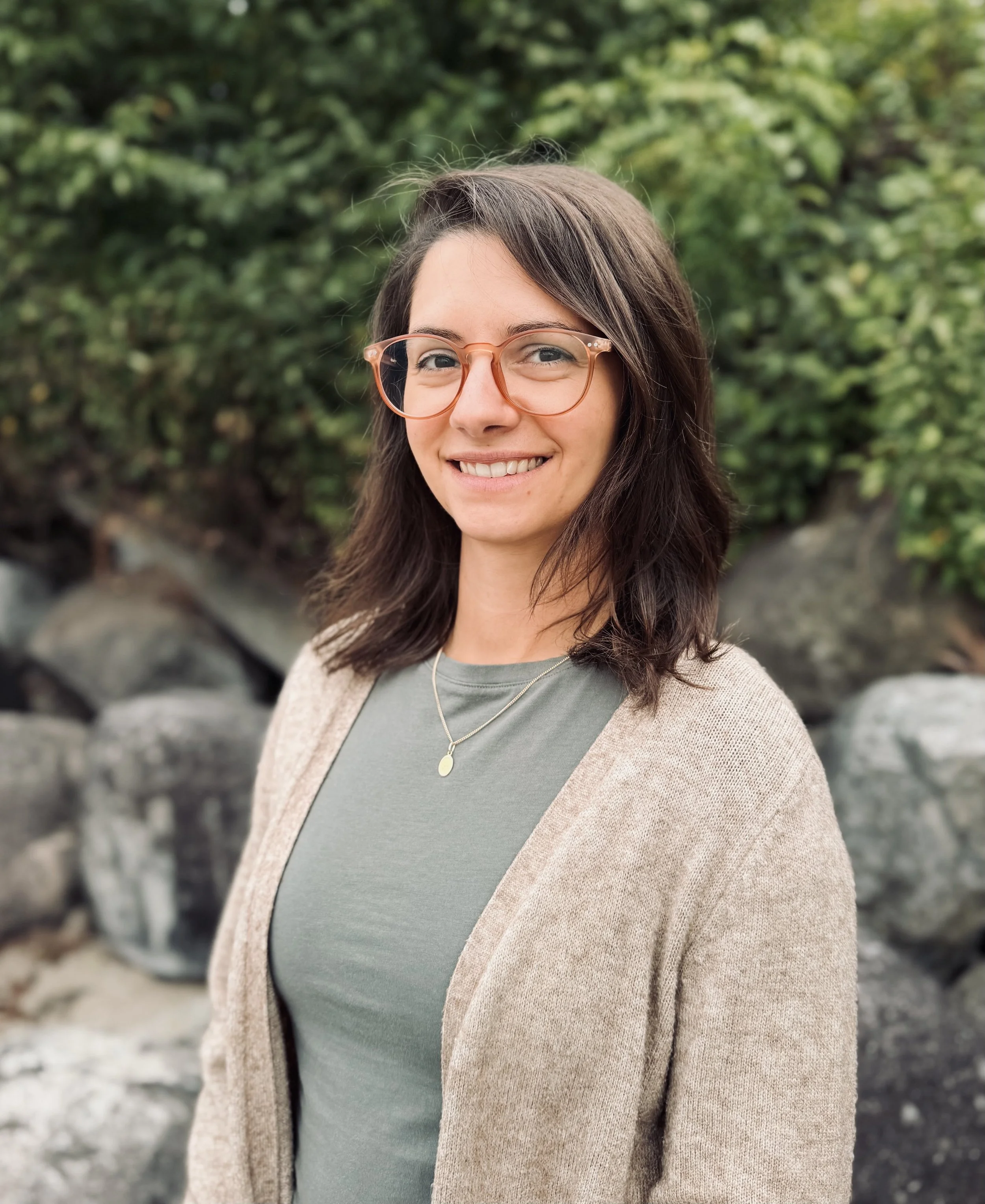 Photo of Nicole Persall, a therapist in Vancouver BC standing in front of greenery on a beach in BC