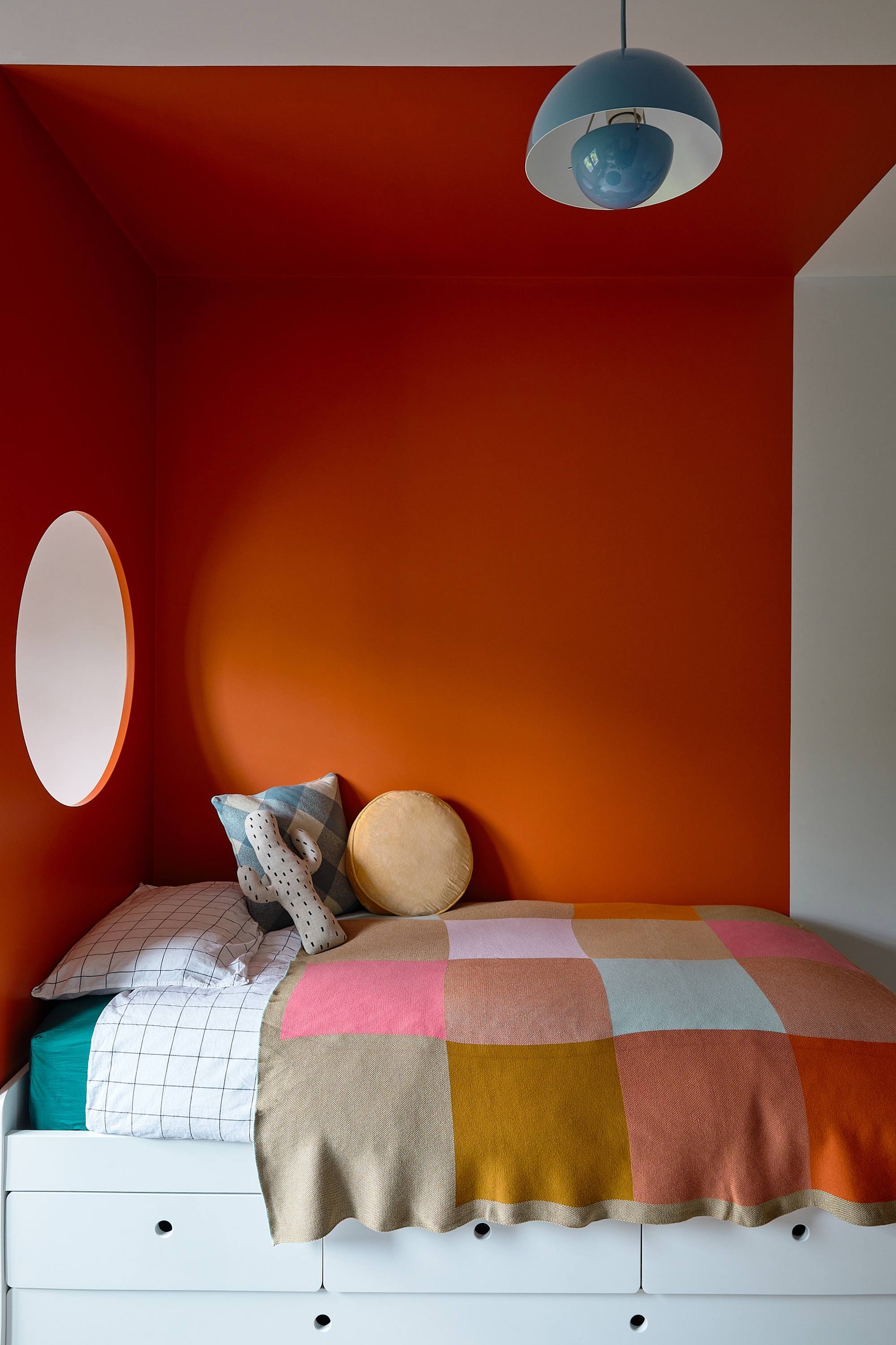 bed-area-with-drawers-underneath-and-orange-wall-with-porthole.jpg