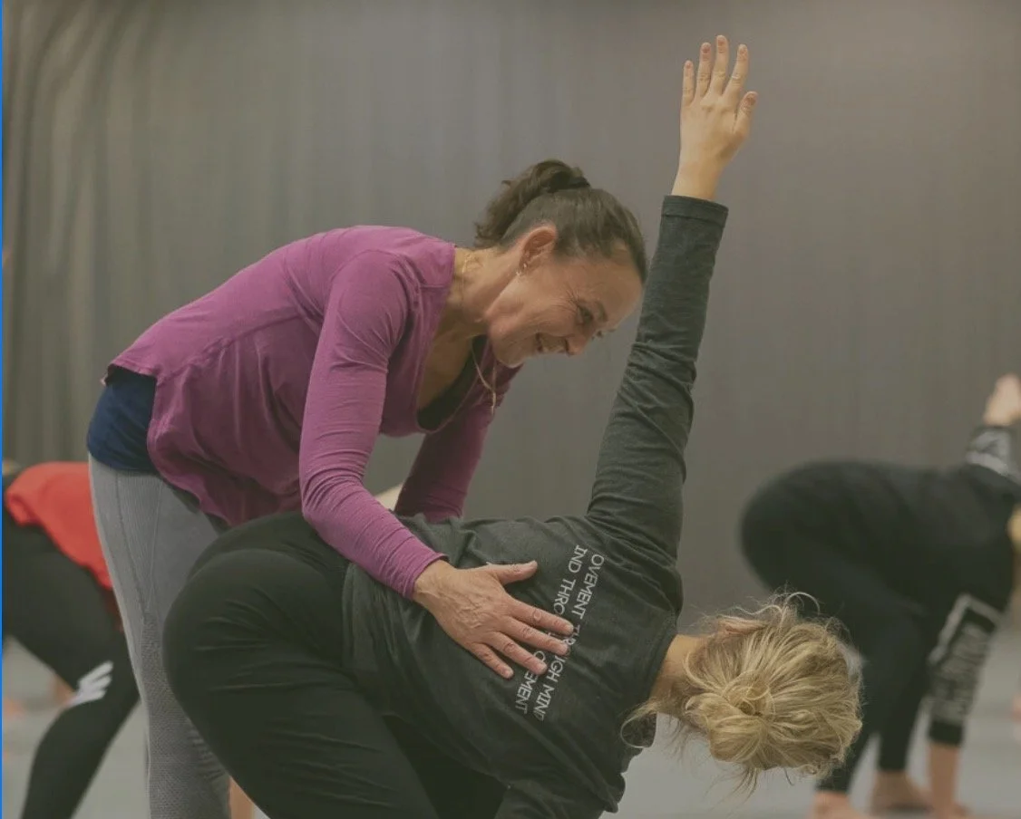 Cecilia Douglas hjälper en annan kvinna med yogaövning i ett träningspass.