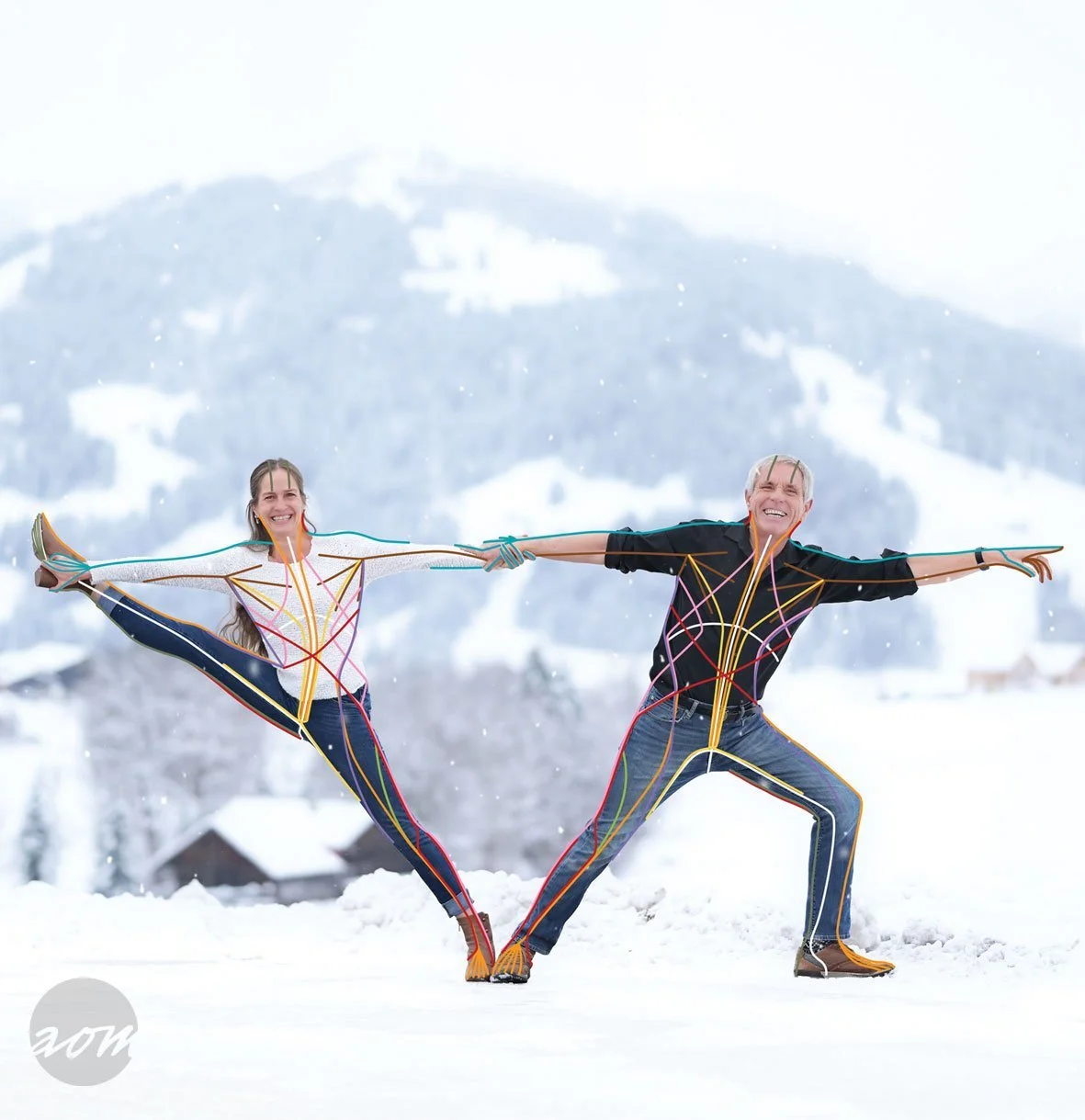 Två personer utomhus i snö, en man och en kvinna, som är bundna av färgglada rep, poserar precis som en lindansare, med ett snötäcktslandskap och berg i bakgrunden. Anatomy Trains in Motion med Cecilia Douglas.