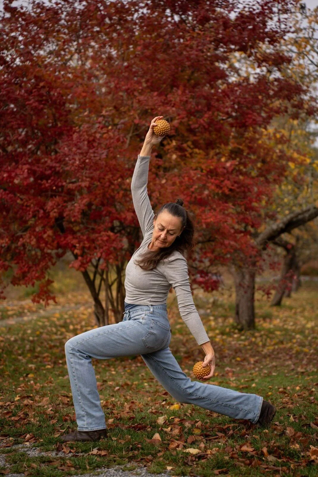 Cecilia Douglas i jeans och grå tröja, poserar i en park om hösten.